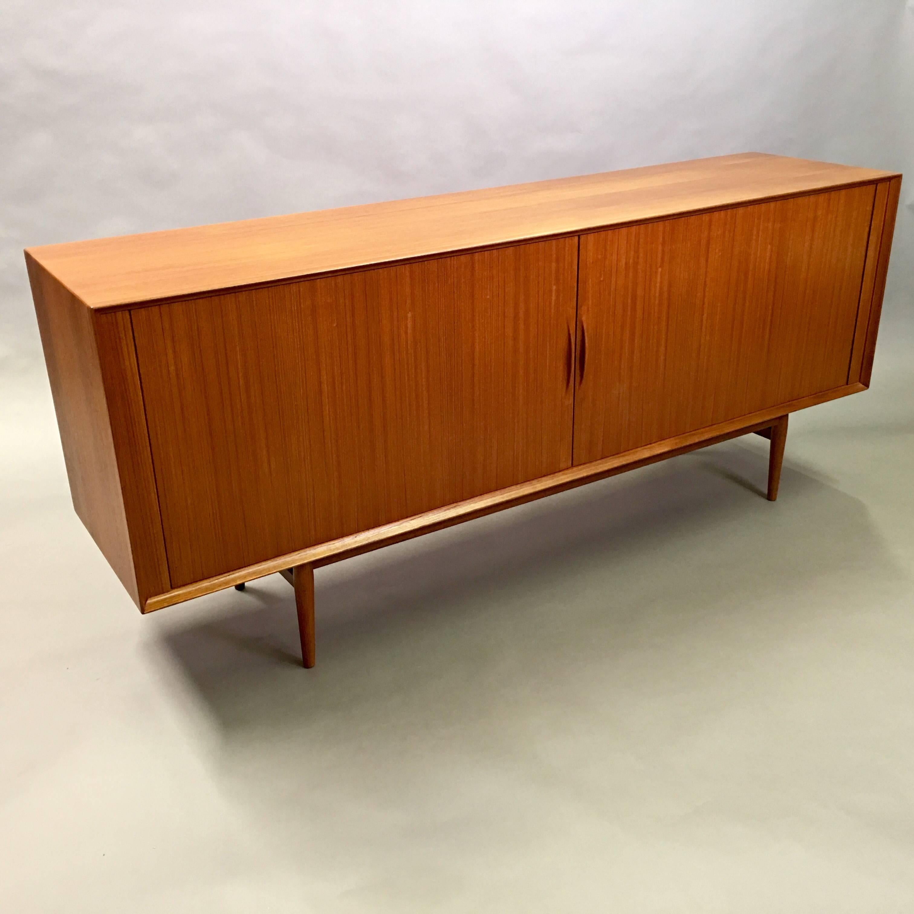 Minimal, Danish Modern, teak credenza by Arne Vodder for Sibast features a tambour front that slides open to reveal adjustable shelves and three drawers.