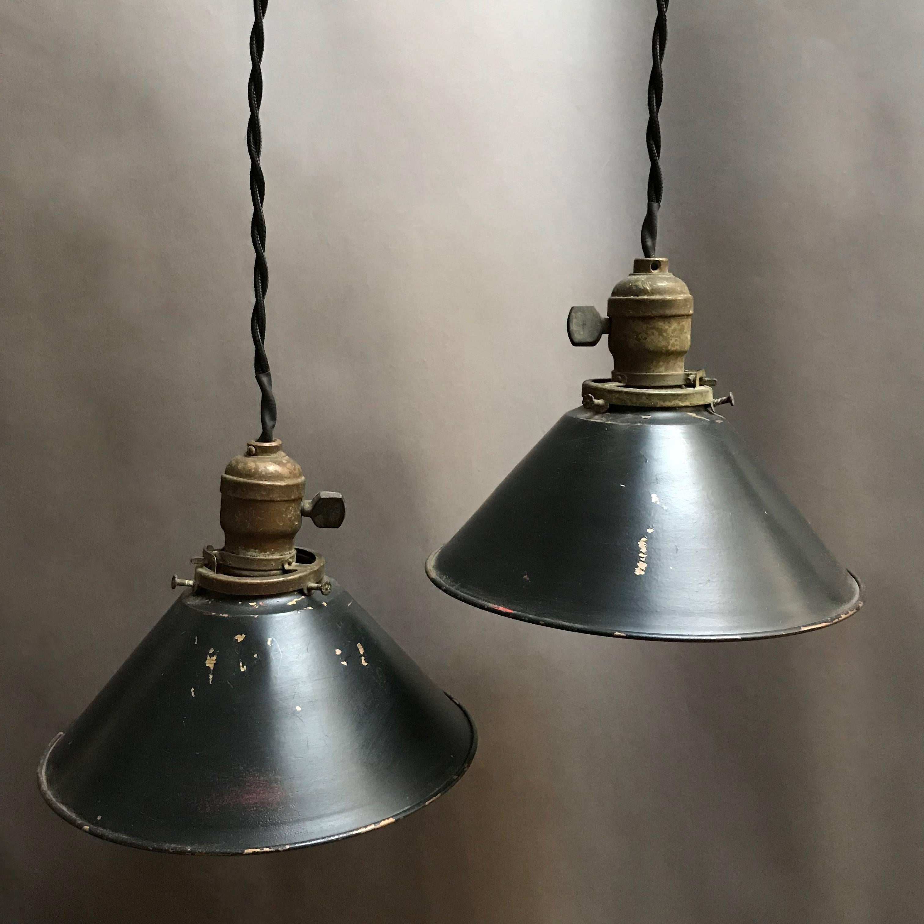 Industrial, painted steel, cone shape, factory pendant lights with brass switch fitters are newly wired with 36 inches of braided cloth cord to accept 150 watts each. The shades have black exteriors and steel interiors.