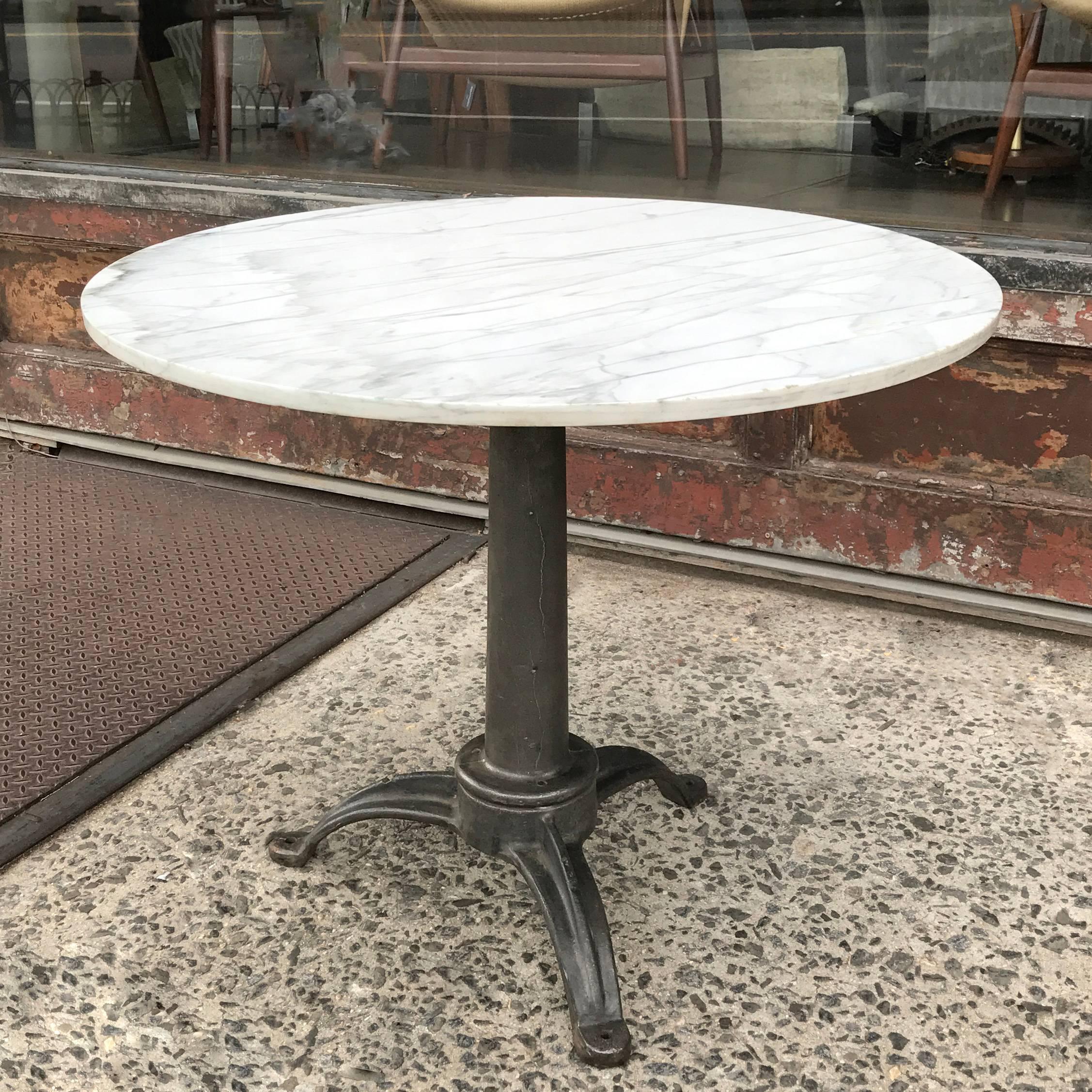 Round, gray and white grain, marble, café dining table with Industrial cast iron pedestal base. Pedestal footprint is 23in. x 23in.