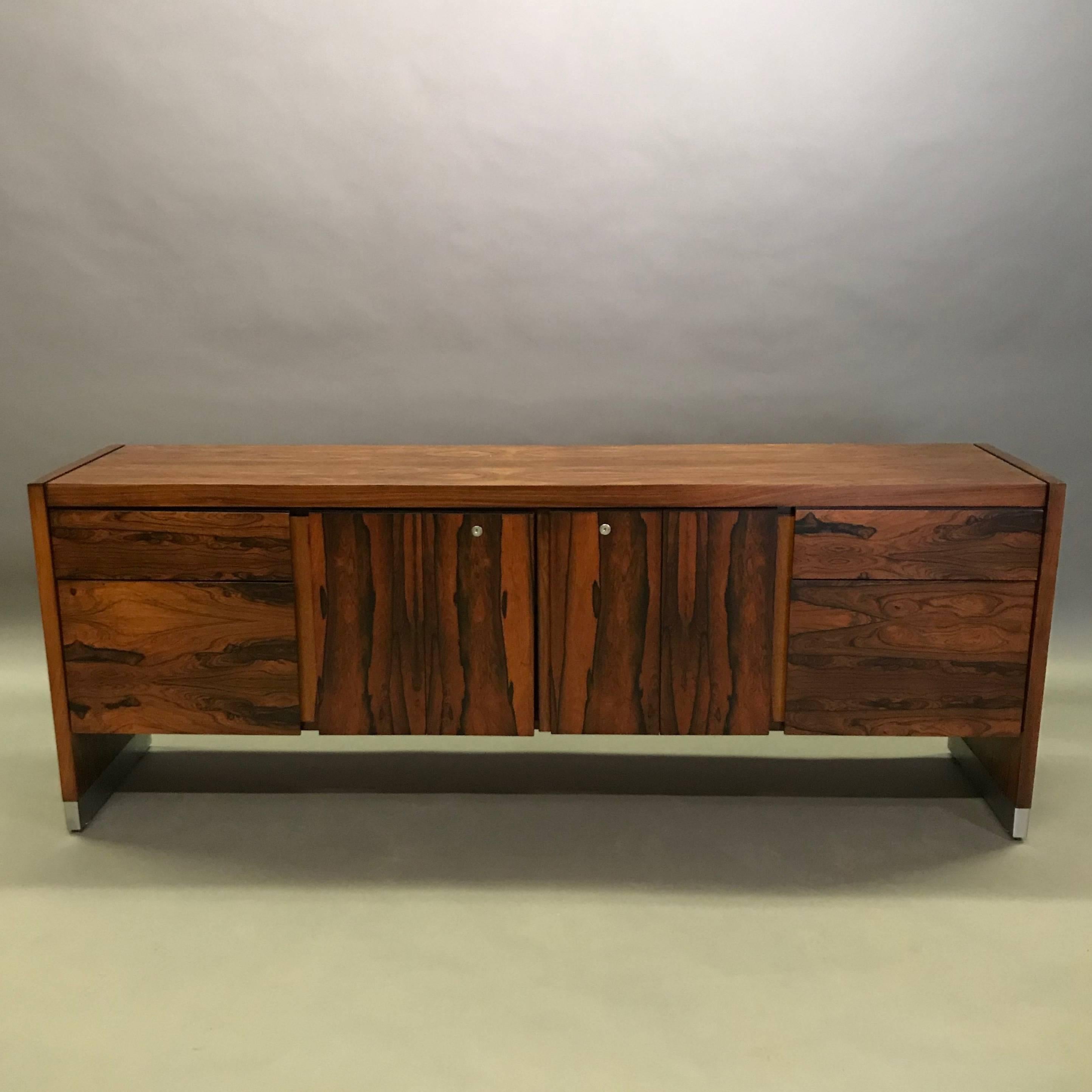 Handsome, 1970s, rosewood veneer, office credenza with chrome details features four drawers and center shelving storage in the center. The back is finished so the credenza can float in a room.