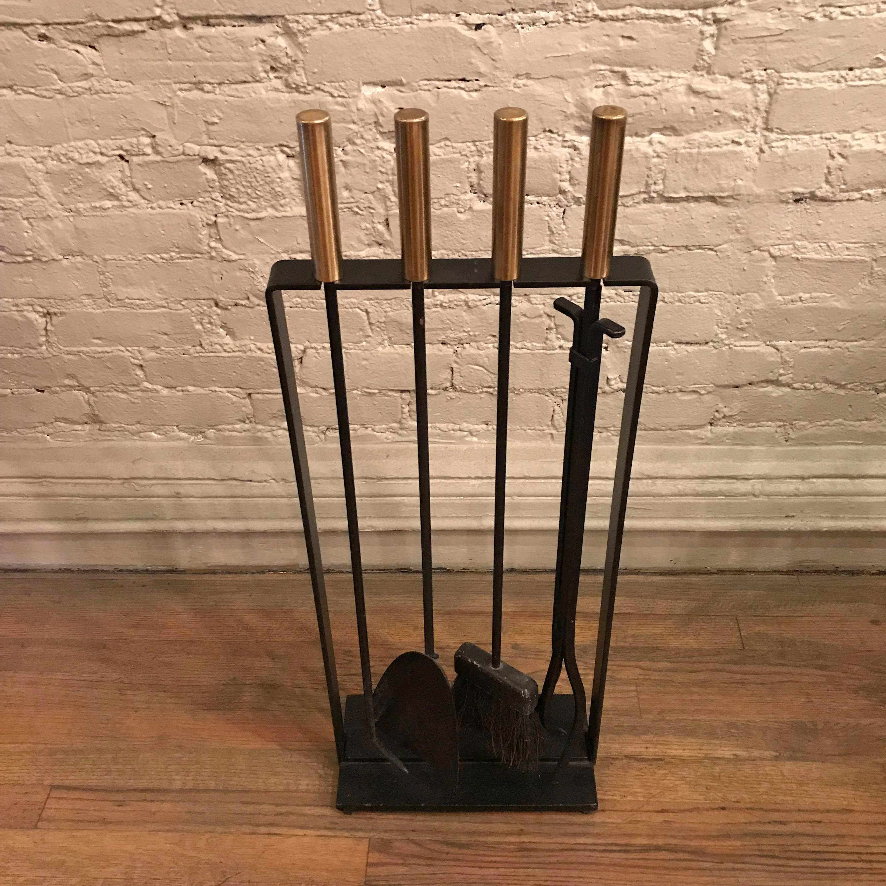 Modernist, four-piece, fireplace tool set by Pilgrim is black wrought iron with polished brass handles.