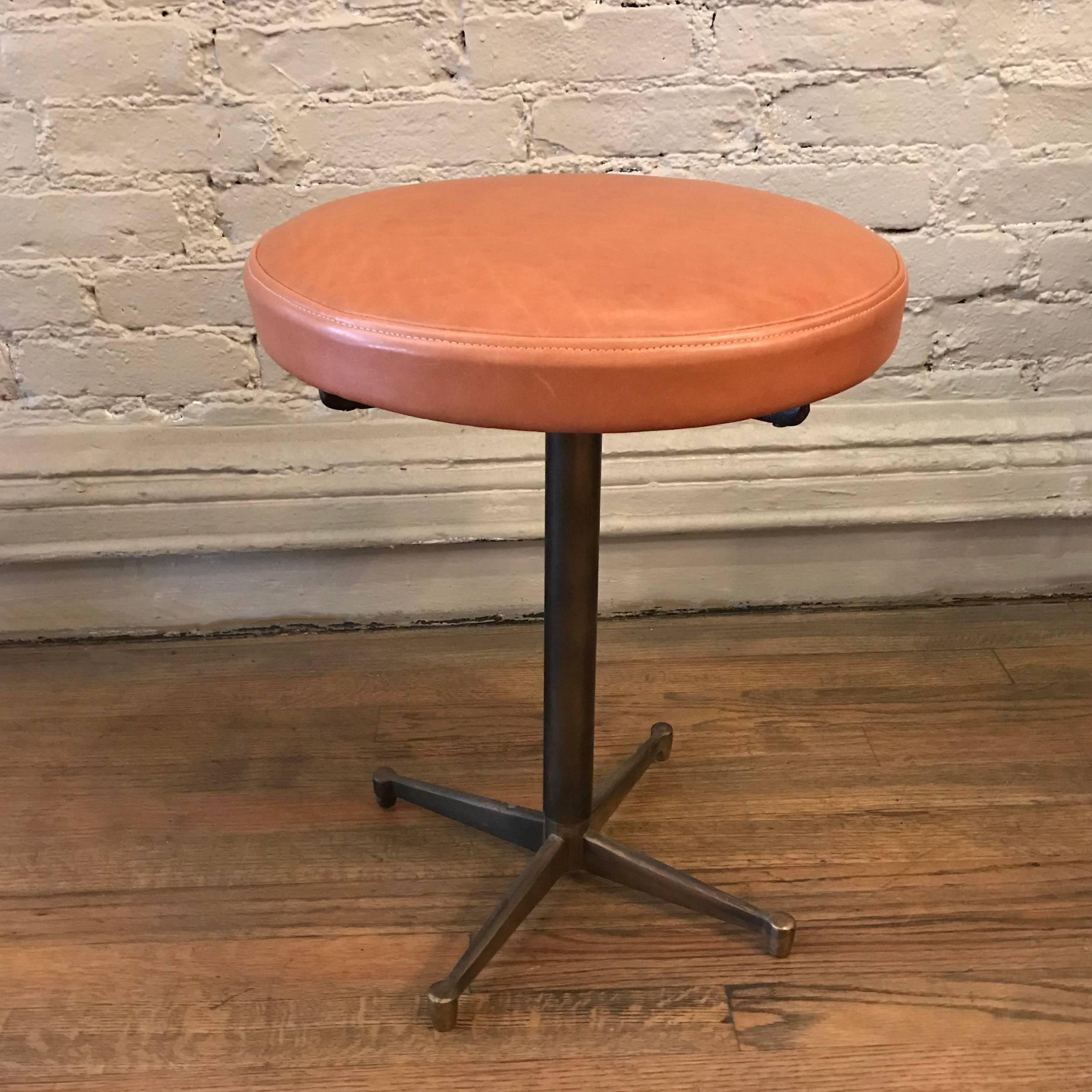 Mid-Century Modern, French, vanity stool features a finely made, minimal bronze base with a newly upholstered swivel seat in tan luggage leather.