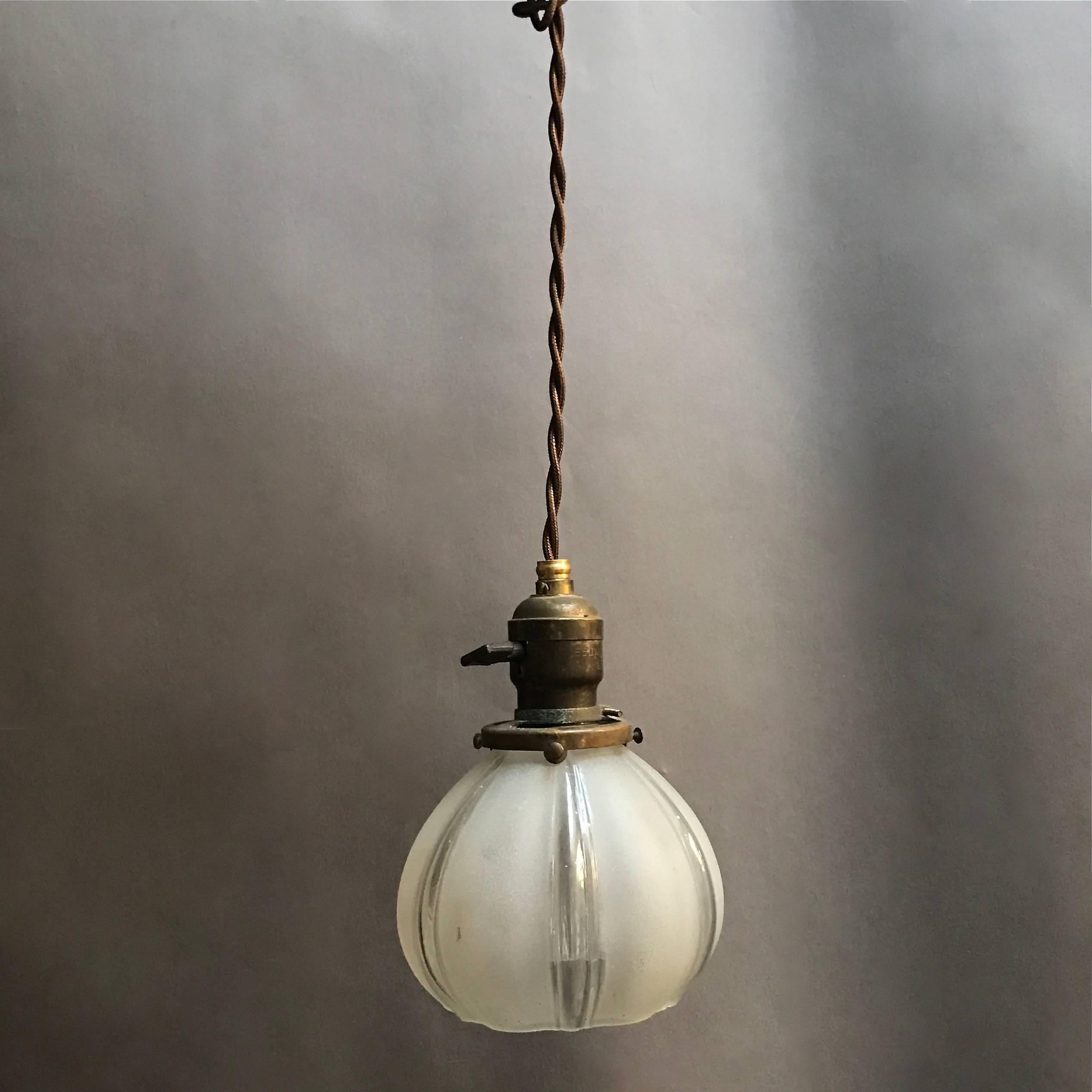Lovely, petite, early 20th century, pendant light features a frosted and clear glass fluted shade, brass fitter and is newly wired for up to 200 watts with 48in. of braided brown cloth cord.