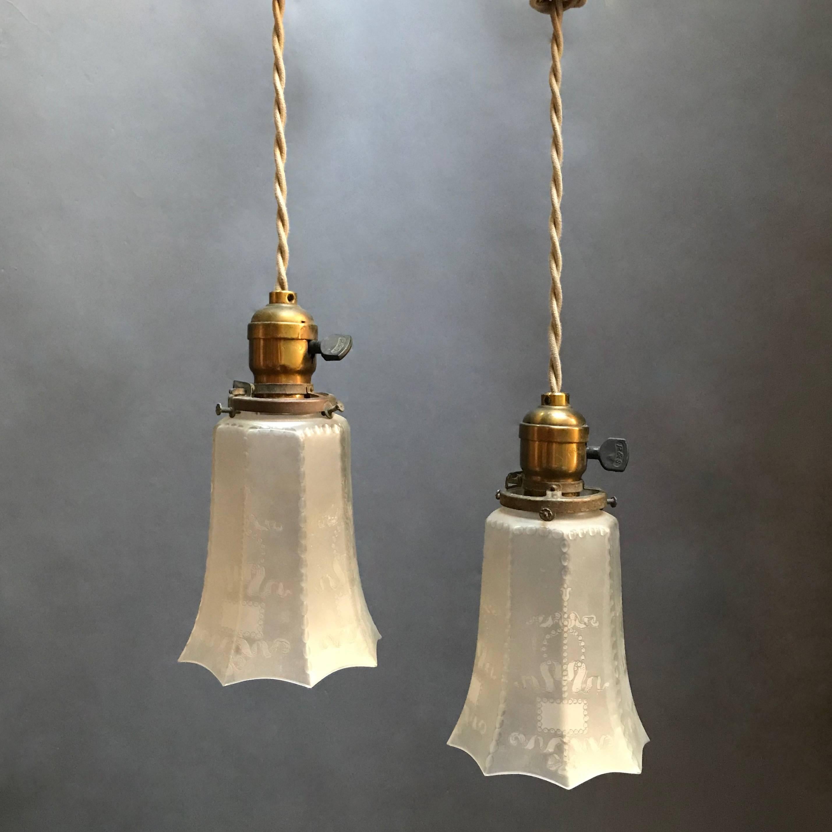 Pair of industrial pendant lights feature faceted and etched, frosted glass shades with scalloped edges on brass fitters with switches, newly wired with 48in of braided cloth cord to accept up to 200 watt bulbs.