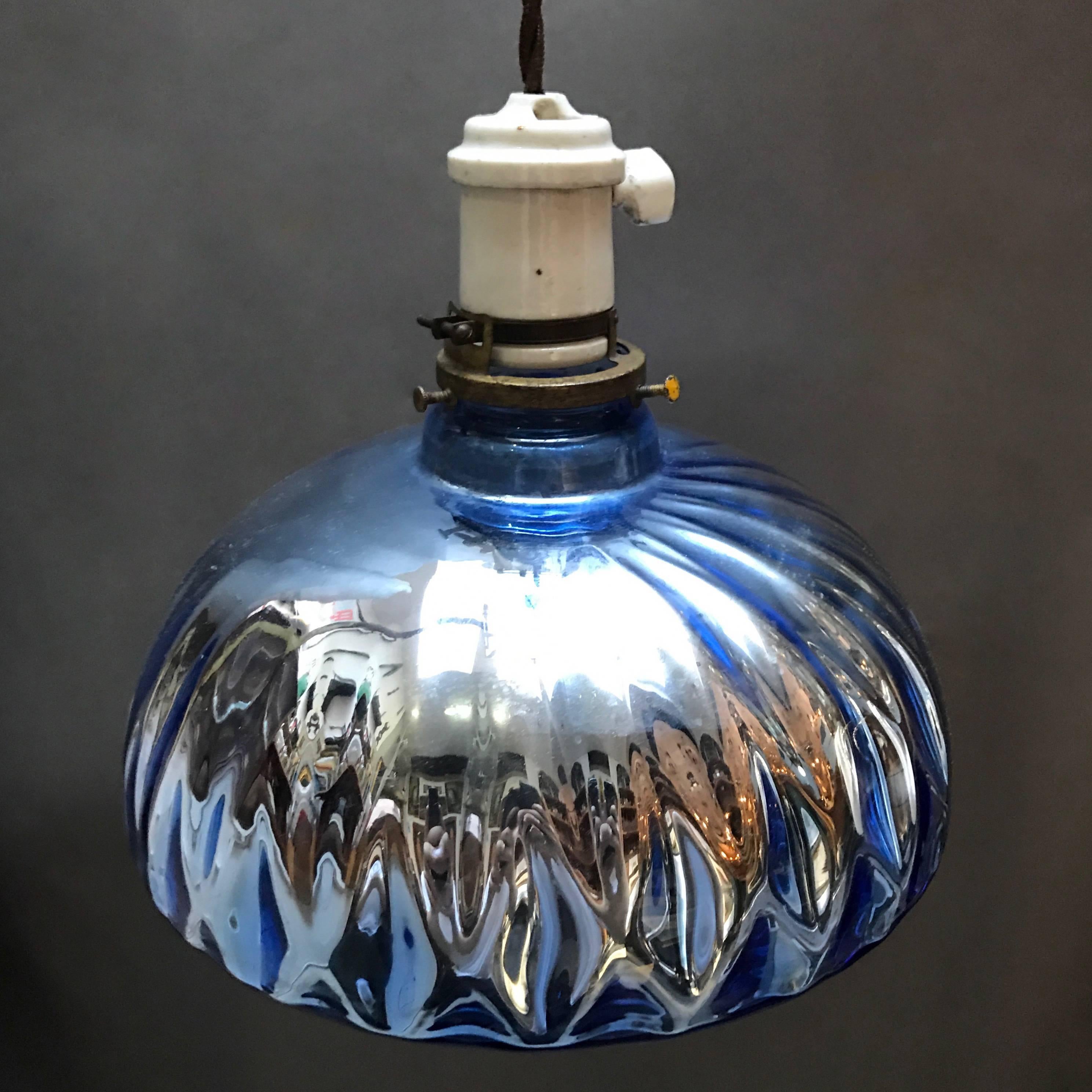 Industrial, 1940s pendant light features a quilted, blue, mercury glass shade with porcelain and brass fitter with switch is newly wired with 48in. of braided cloth cloth cord to accept up to 200 watts .