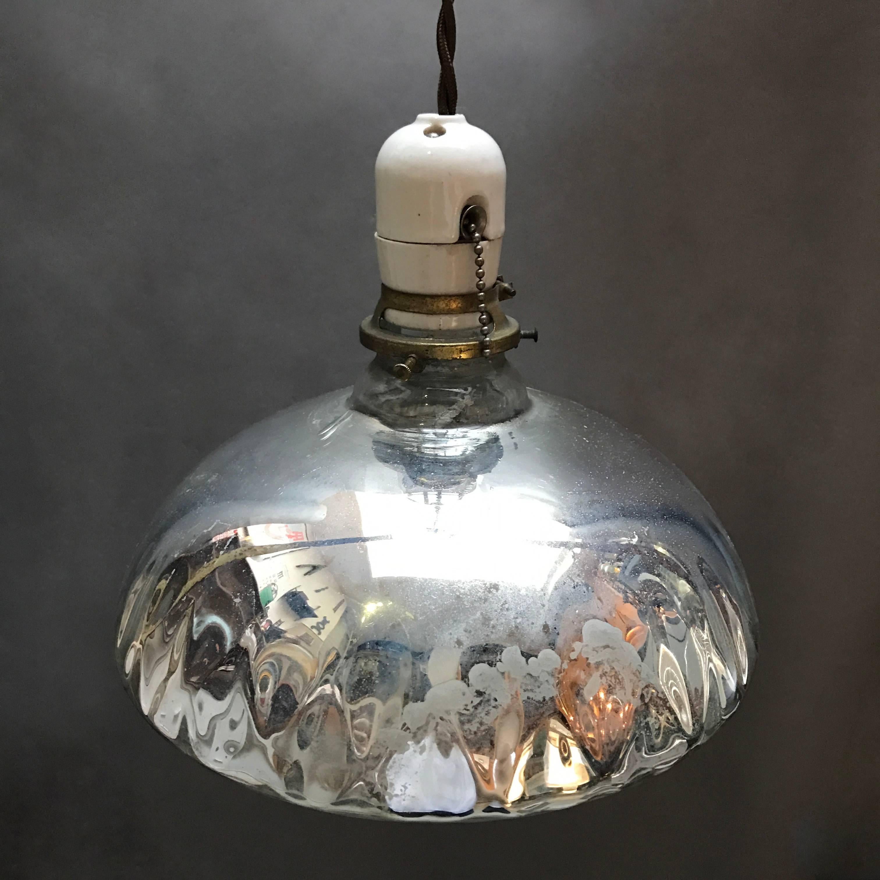 Industrial, 1940s, pendant light features a quilted, silver, mercury glass shade with porcelain and brass fitter with pull chain is newly wired with 48 in. of braided cloth cord to accept up to 200 watts .