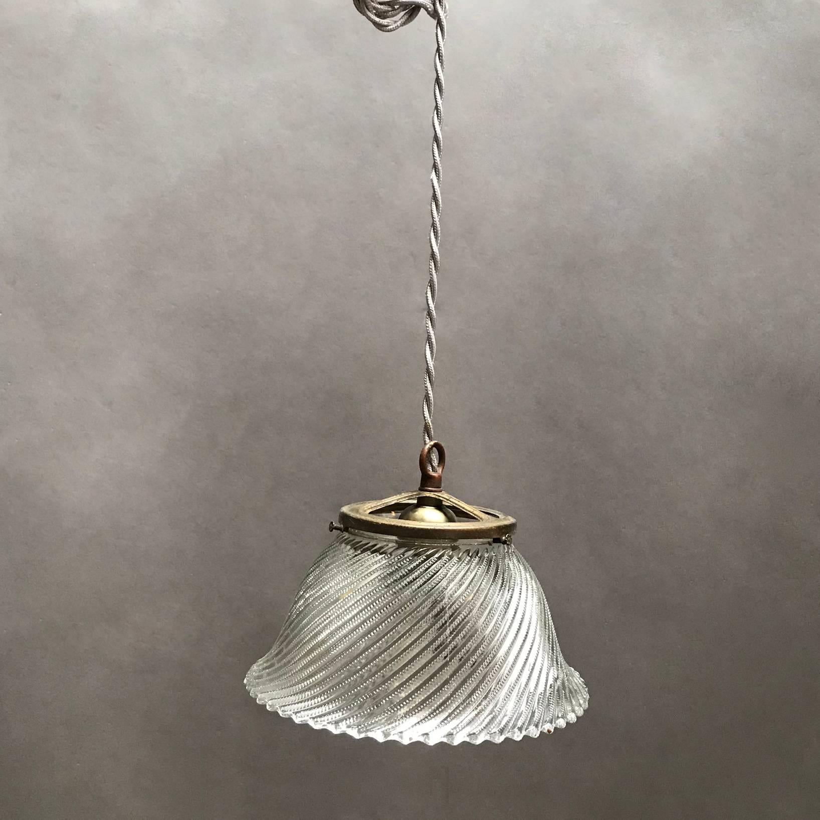 Industrial, 1920s, Holophane glass, bell pendant light features intricately cut, swirled shade with open, wide brass fitter is newly wired to accept 200 watt bulbs with 48in. of braided cloth cord.