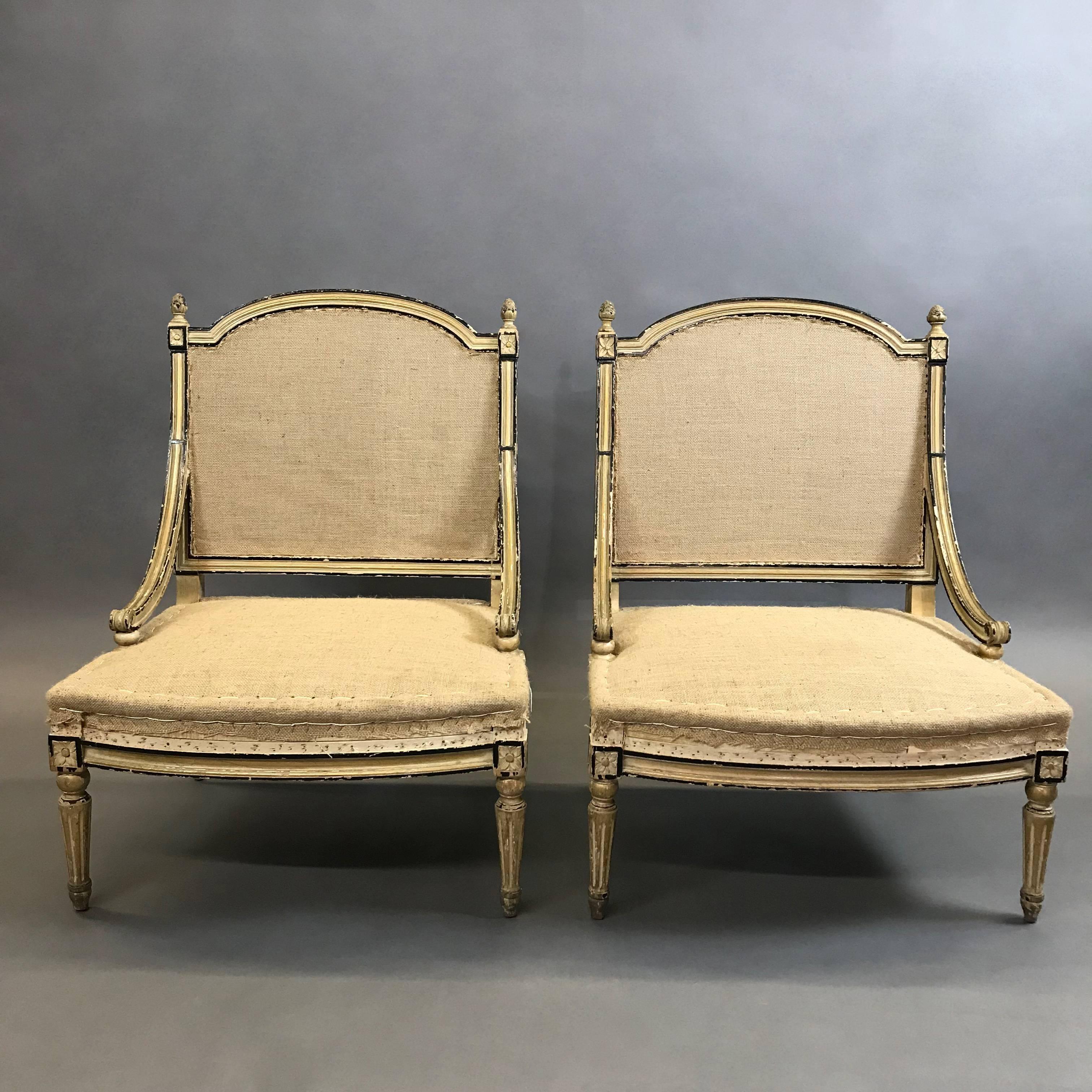 Early 20th century, stately, Bergère chairs in the style of Louis XVI feature painted gilt mahogany frames with black trim and low, deep seats. Shown upholstered in burlap; custom cushioning and upholstery available.