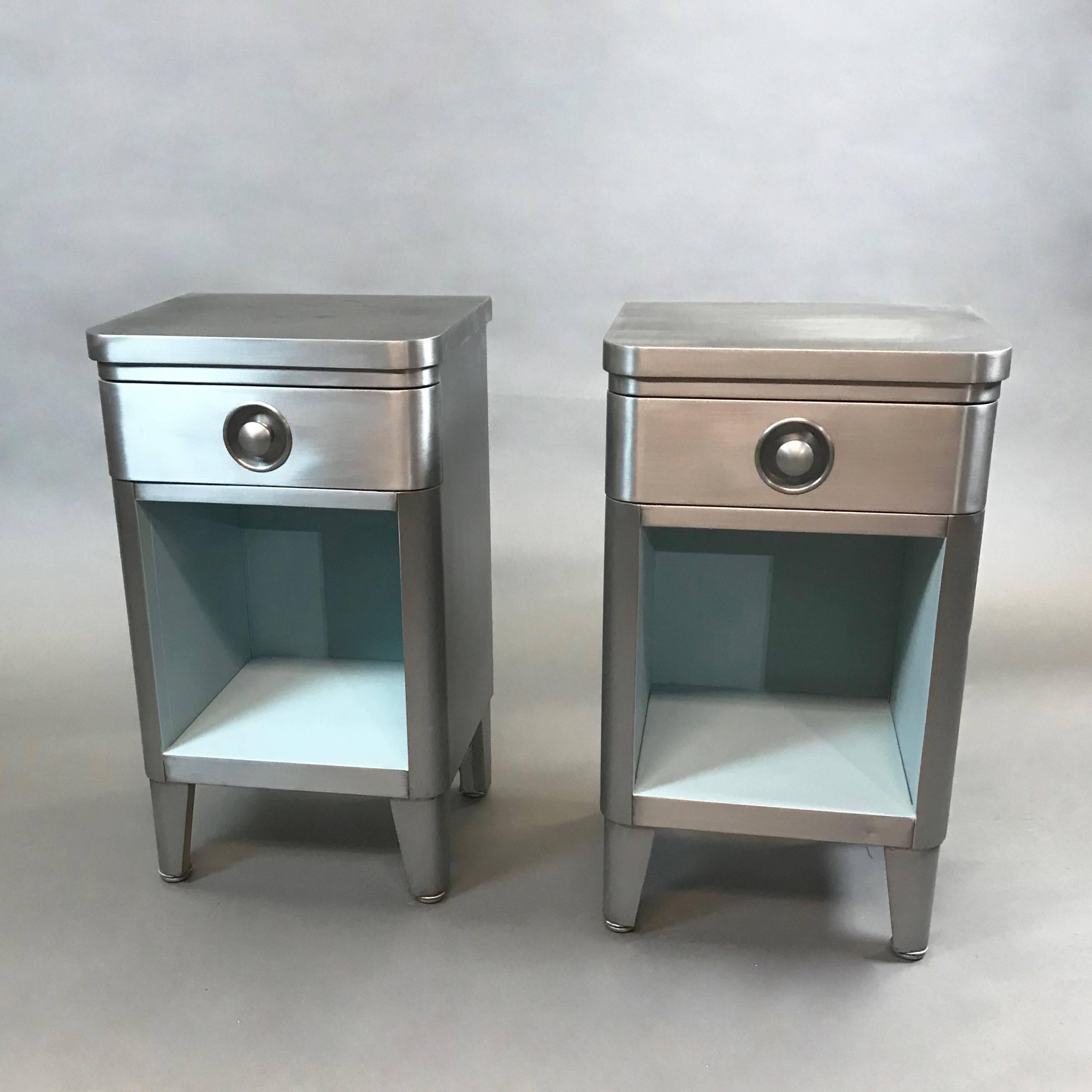 Pair of machine-age, Art Deco, Industrial, brushed steel nightstands or end tables by Norman Bel Geddes for Simmons Furniture with recessed pulls and contrasting powder blue interiors.