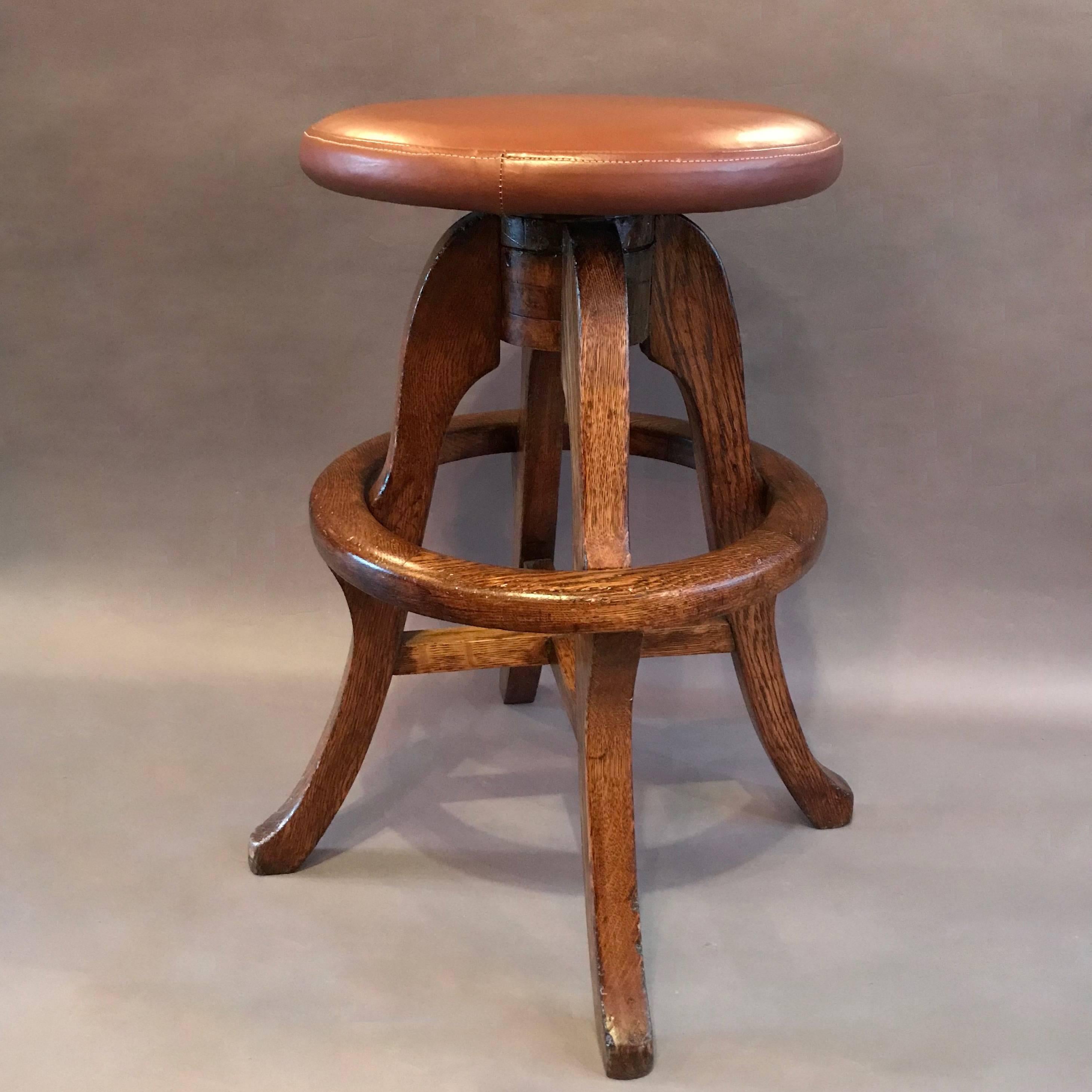 1930's, solid oak, workshop stool with newly upholstered caramel brown leather seat. The diameter of the seat is 14in and the foot ring is 13in high.