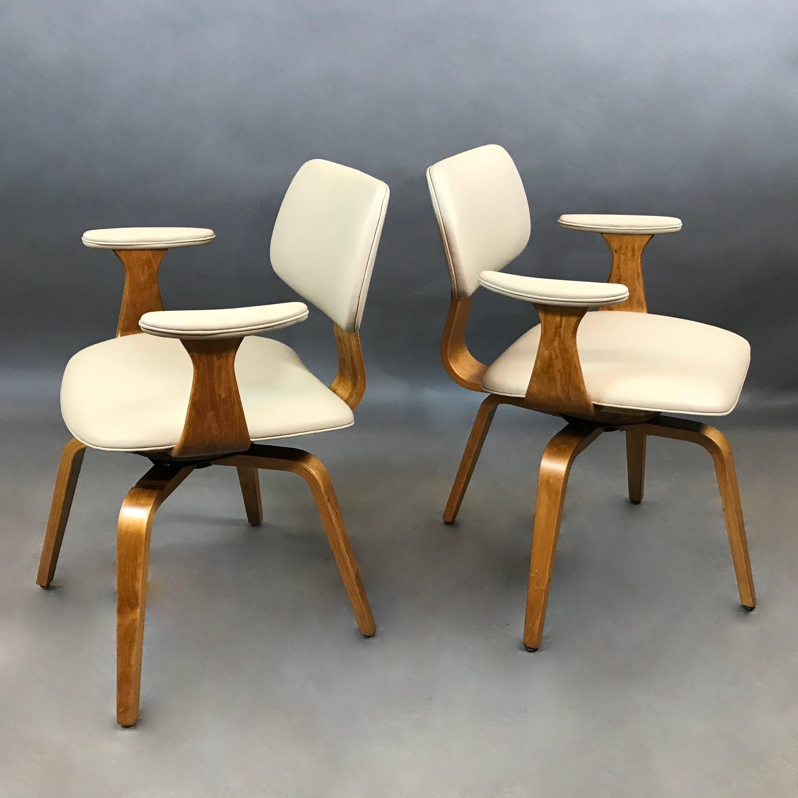 Pair of Mid-Century Modern, bent maple, swivel armchairs by Thonet with newly upholstered seats, backs and armrests in cream leather. Measure: The arm height is 26 inches.