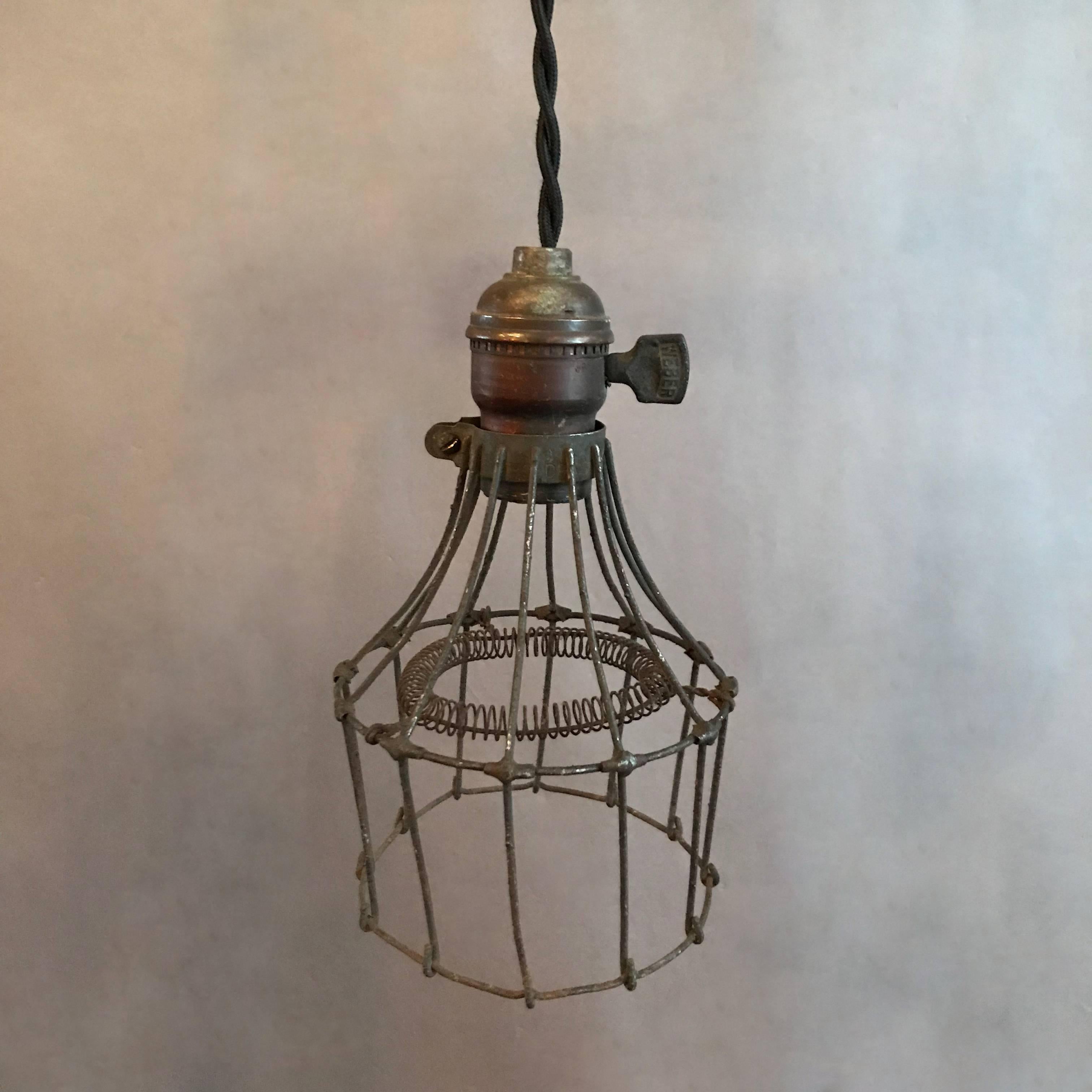 Unusual and rare, 1920s, industrial, utility, cage pendant light features a steel wire cage with interior coiled bulb protection and brass fitter with switch. The light is newly wired to accept up to a 200 watt bulb with 48in. of braided cloth cord.