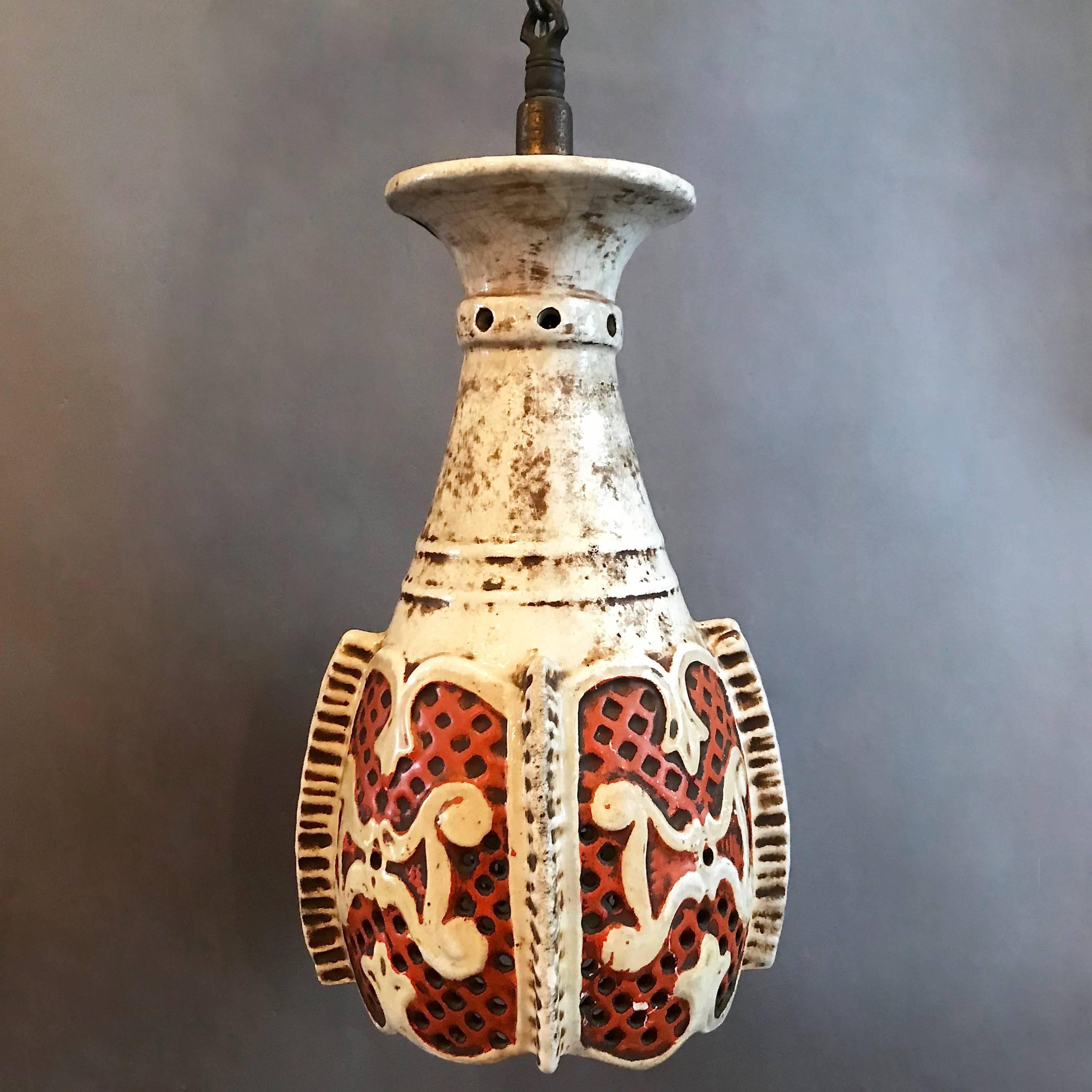Vintage, midcentury, Moorish pendant light features a patinated, white and deep orange ceramic shade with perforated body on a brass fitter and chain. This light has been rewired for 150 watts bulb with 16 in of chain.
