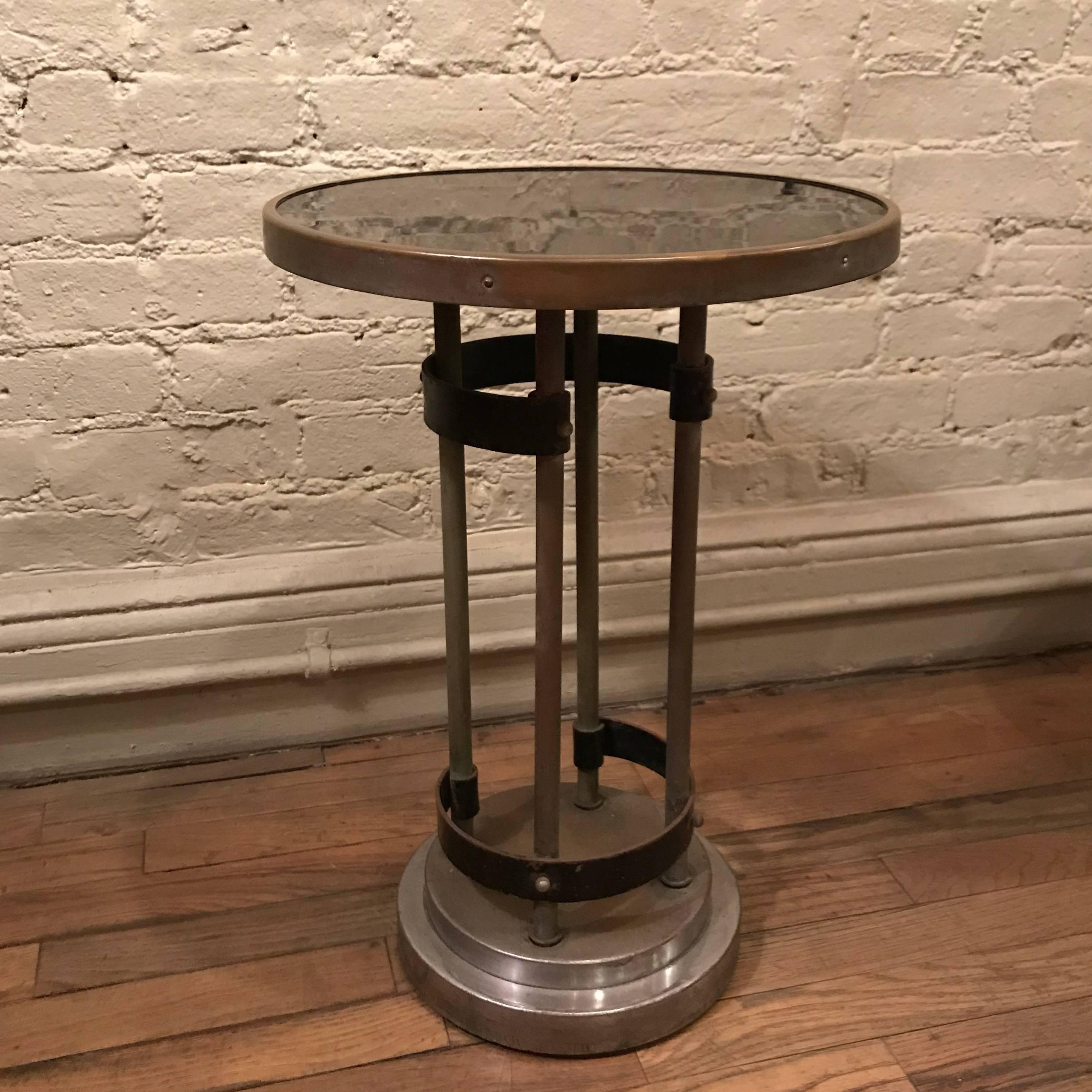Art Deco side table by Gilbert Rohde features a round laminate top with brass trim and chrome stepped base with brass stems and painted metal braces.