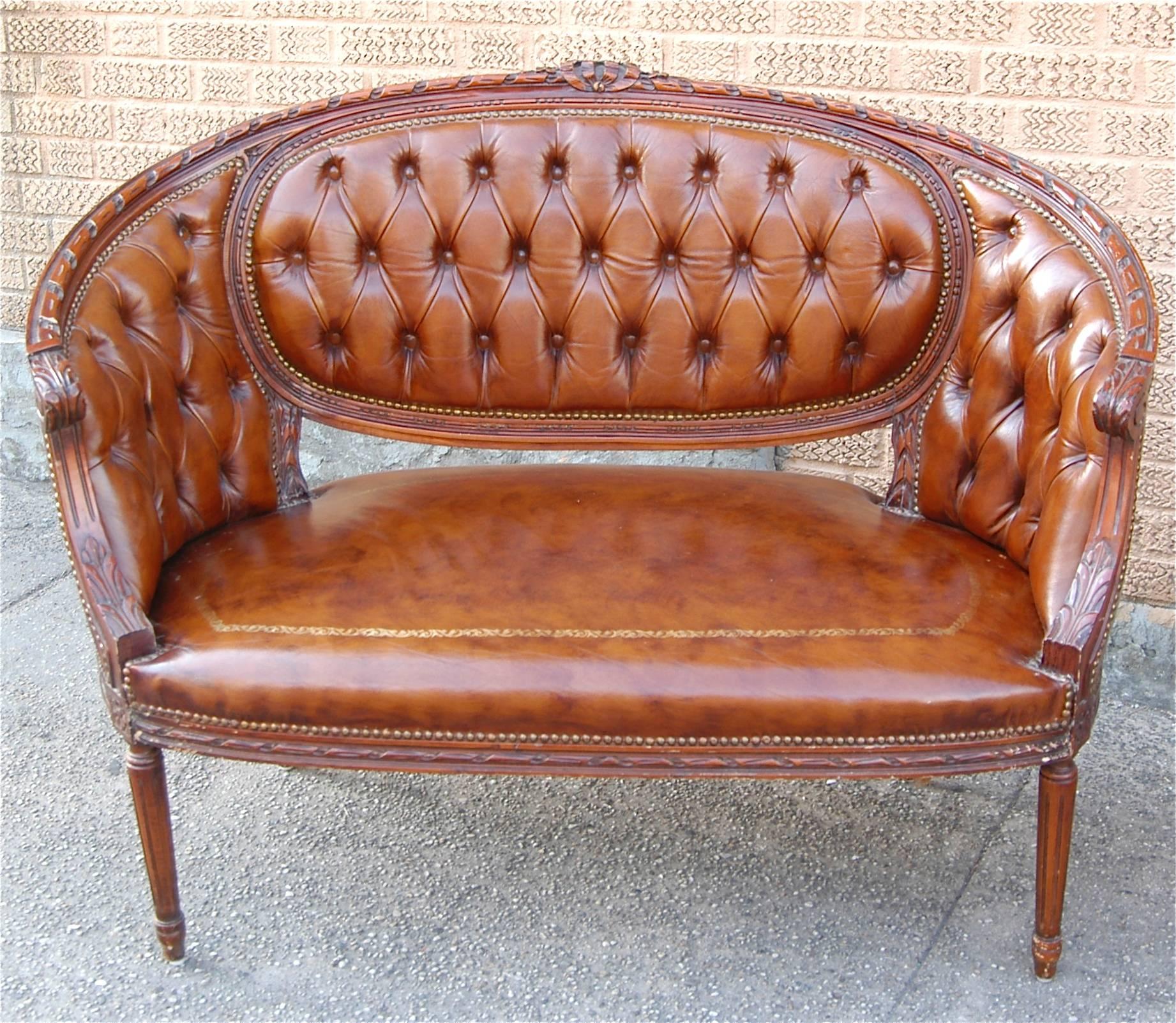 Pair of Italian, leather tufted, settees / canapés / loveseats with intricately carved wood frames and nailhead trim, circa 1970s, marked made in Italy.
