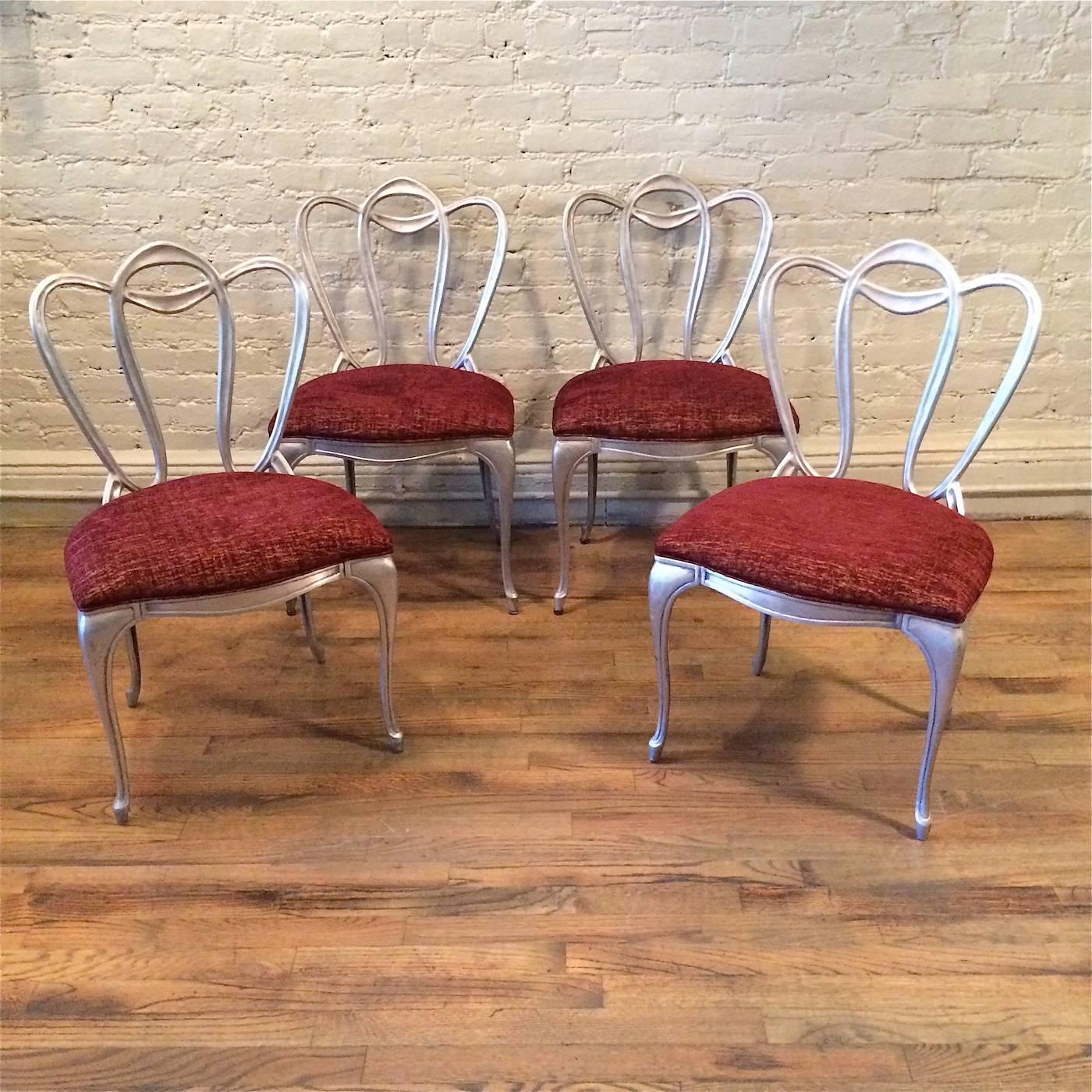 Ensemble de quatre chaises Art Nouveau, Hollywood Regency, avec un motif organique de vigne, les cadres en aluminium moulé sont nouvellement tapissés dans un riche velours contrastant, bordeaux et or. La table Vitrolite illustrée est vendue