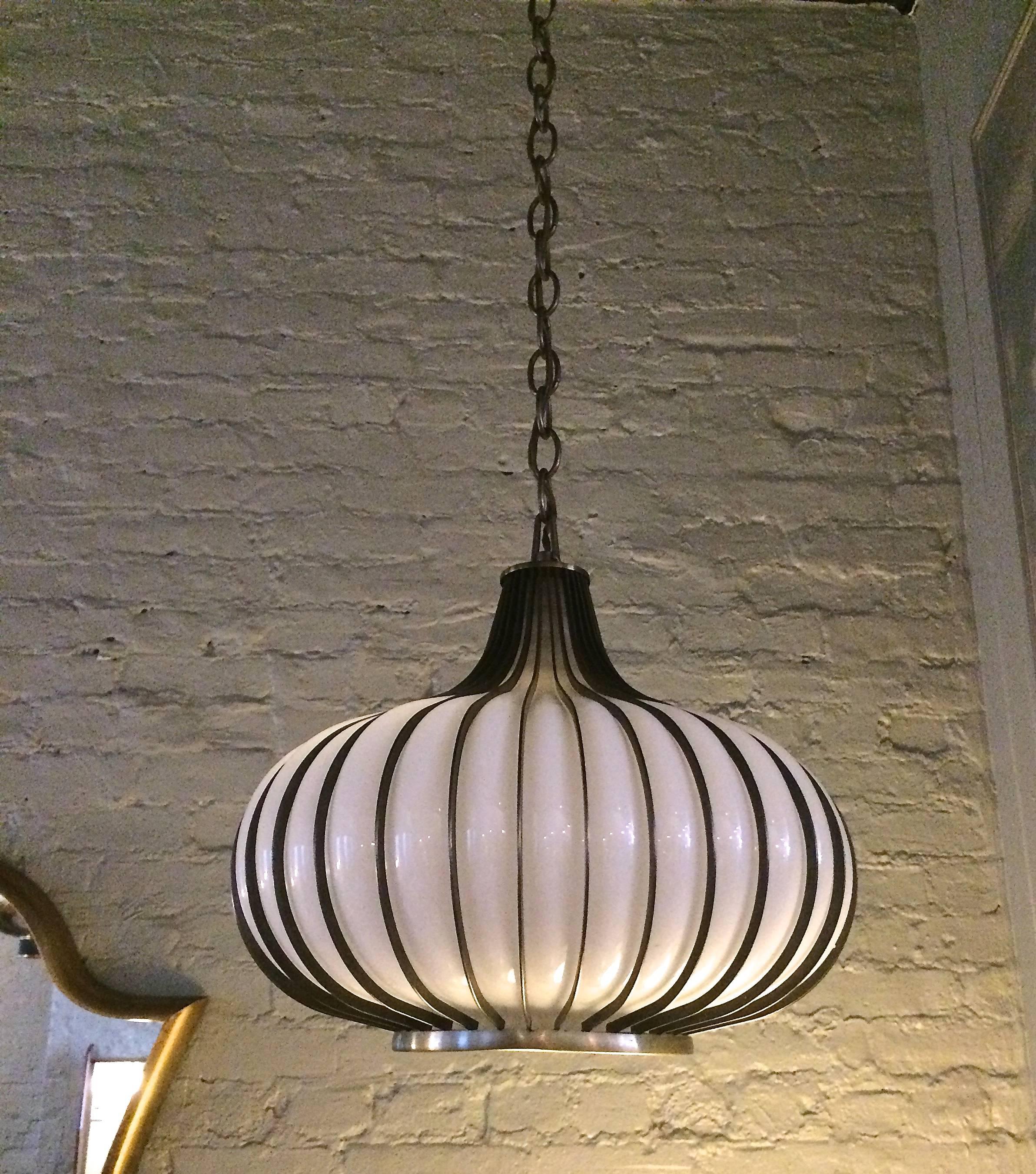 Mid century, Hollywood Regency, garlic-shaped, swag, pendant light with
blown milk glass shade encased in a steel frame.