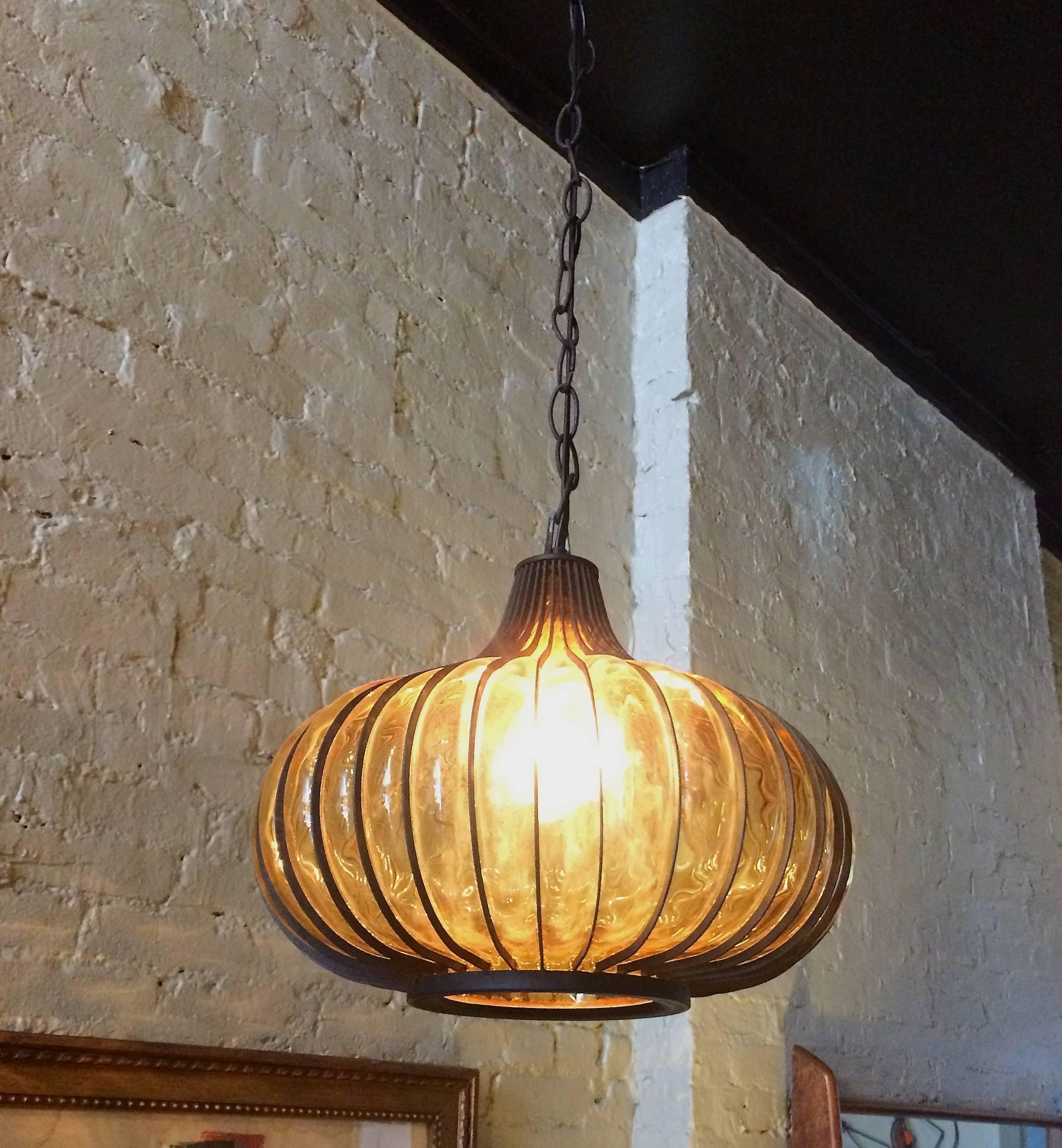 Midcentury, Hollywood regency, garlic-shaped, swag, pendant light with
blown amber glass shade encased in a steel frame.