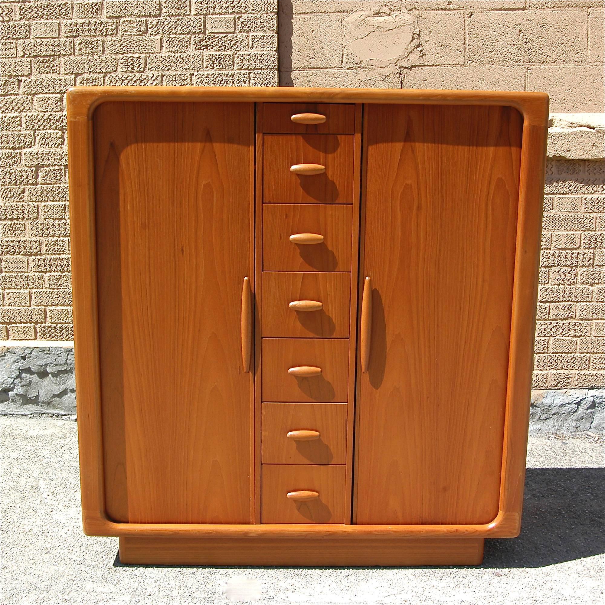 Danish modern, teak, highboy, gentleman's dresser by Dyrlund with a center row of small drawers and tambour side doors that open to reveal adjustable shelves and pull out drawers. 2 available.