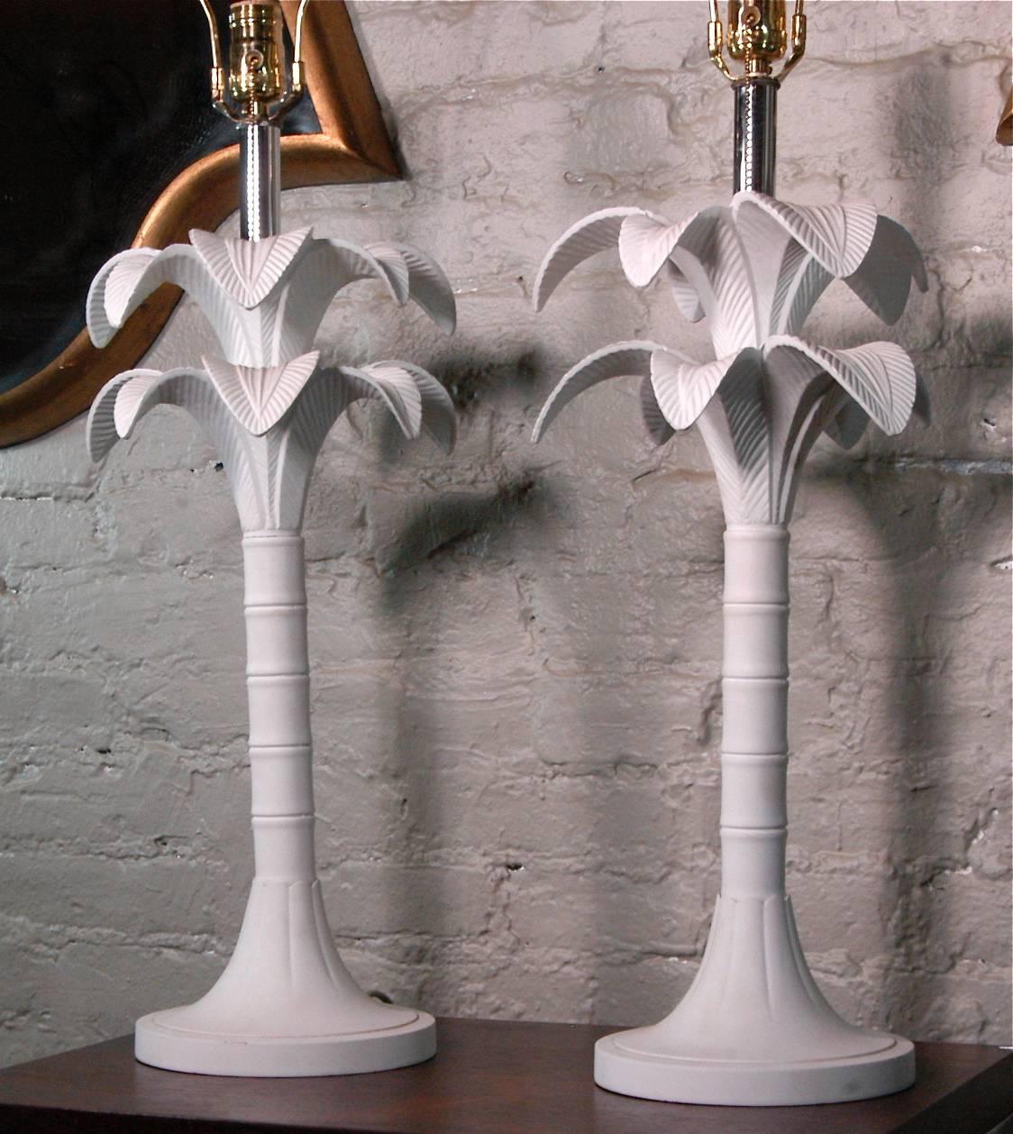 Lovely pair of Hollywood Regency table lamps featuring stems of cast metal palm trees lacquered in a white matte finish with chrome accents.

The lamps measure: 32.5in height to the top of the harp, 10in diameter at the leaves and 8in diameter at