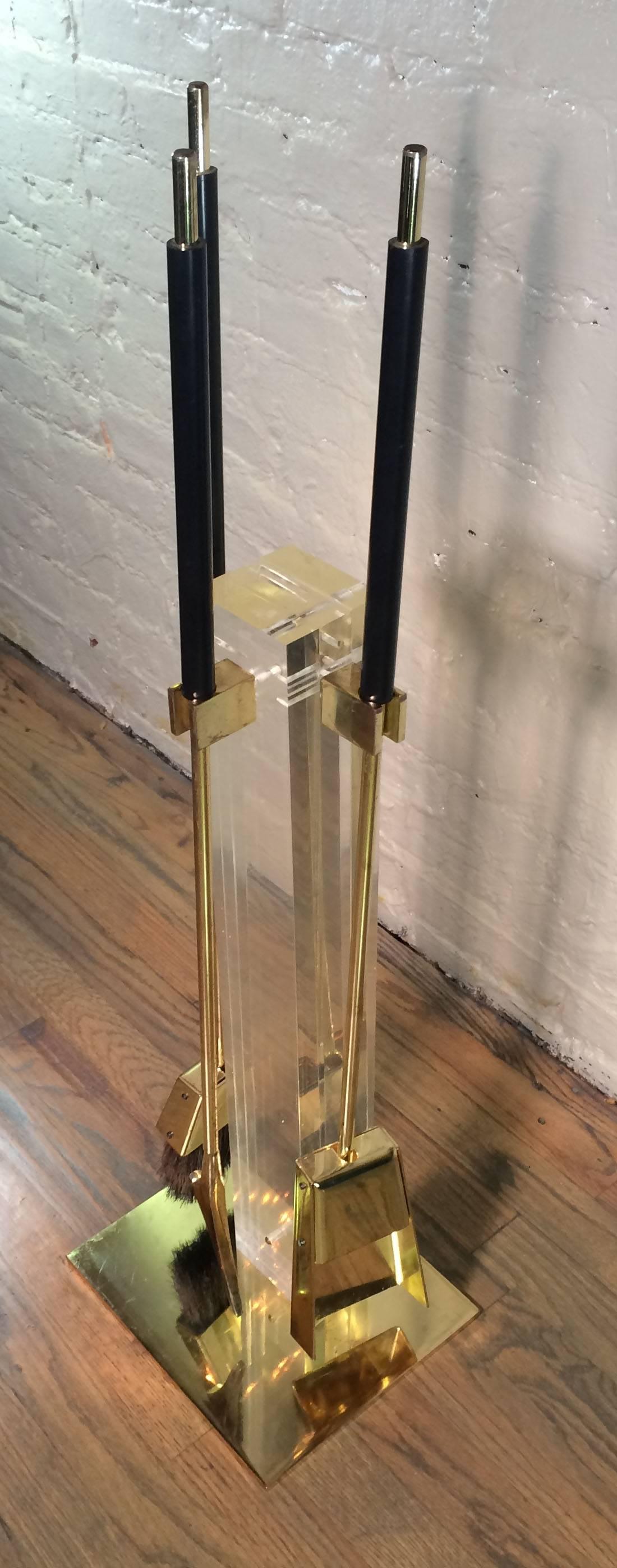 Four-piece set of clear Lucite and brass plated fireplace tools by Alessandro Albrizzi. Clear lucite post with brass plated tools and tool pegs. Handles are black acrylic. 