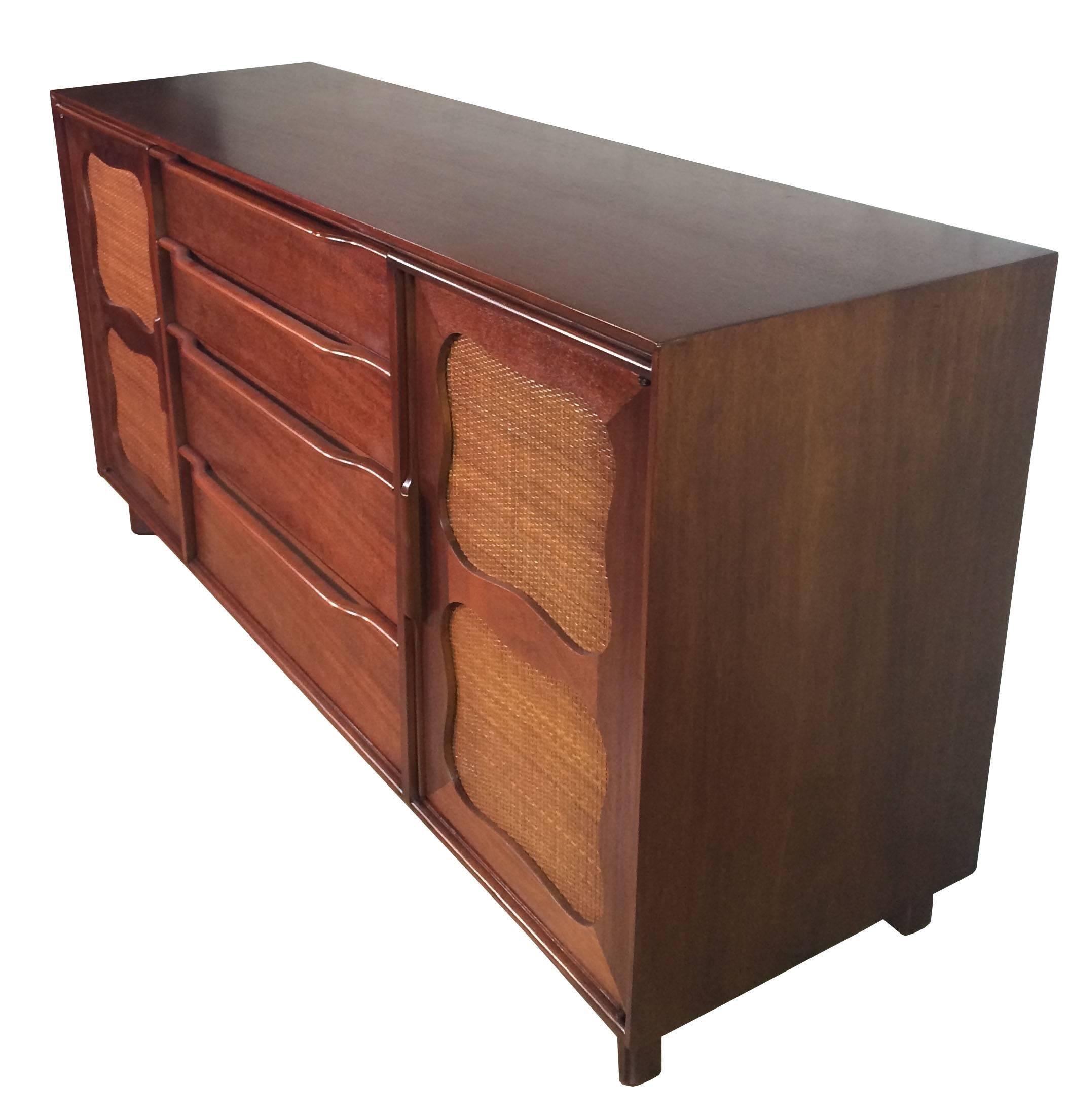 Mid-century, mahogany credenza / sideboard / server by Hickory Manufacturing Company with 4 center drawers, top one has 5 felted compartments, and 2 side doors with decorative rattan details with shelves inside and matching sculpted handles and legs
