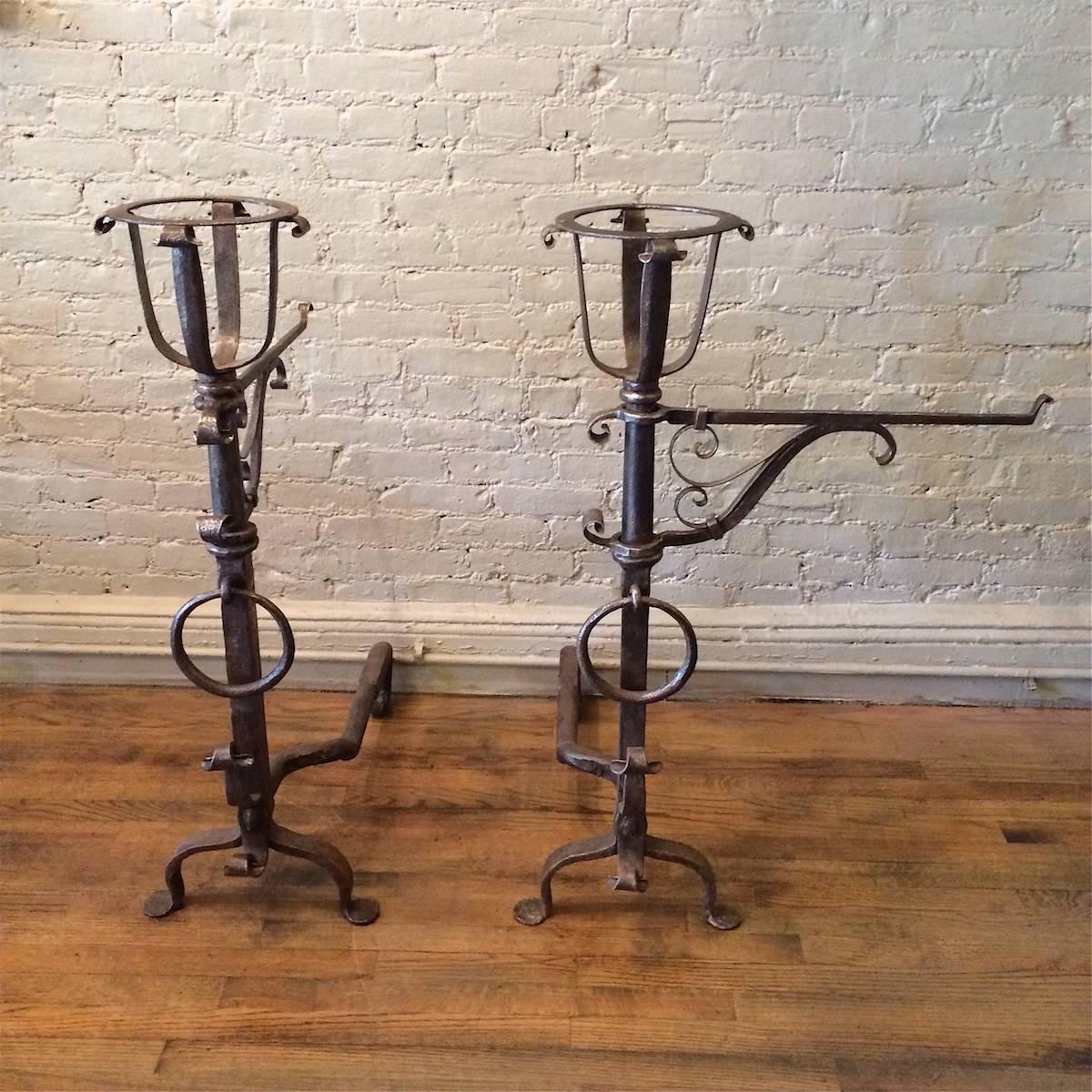 Pair of tall, impressive, 19th century, Gothic style, hand-wrought iron andirons in the style of Samuel Yellin with open basket finials, ring loops and decorative flourishes that are truly a statement for a fireplace.