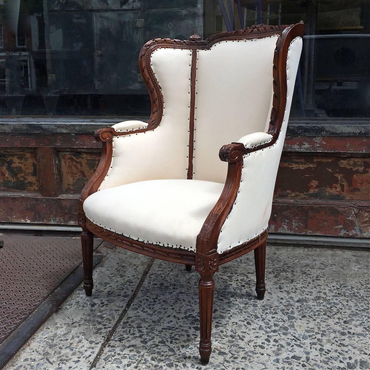 High, wingback armchair in an Edwardian style with ornately carved mahogany frame and muslin upholstery. We can offer upholstery for an additional $400.