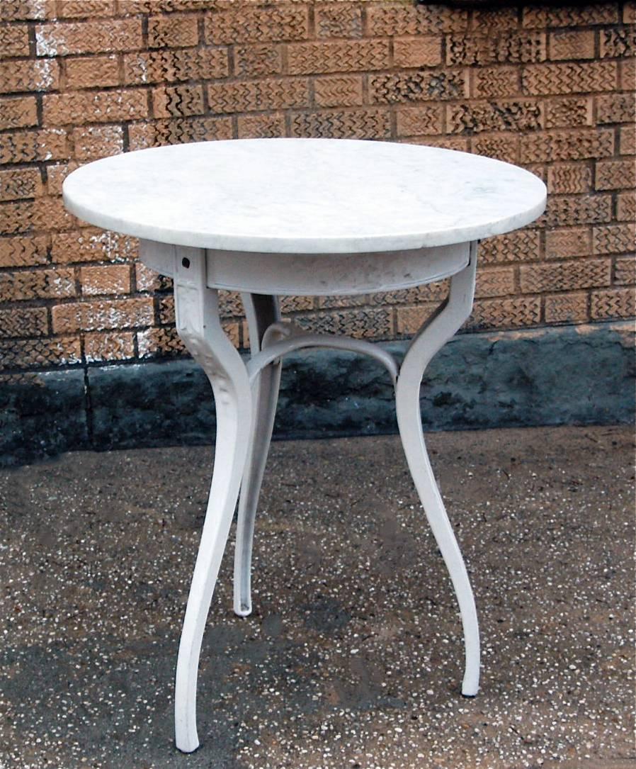 Round white marble café table with ornate cast iron base and finished in baked enamel.