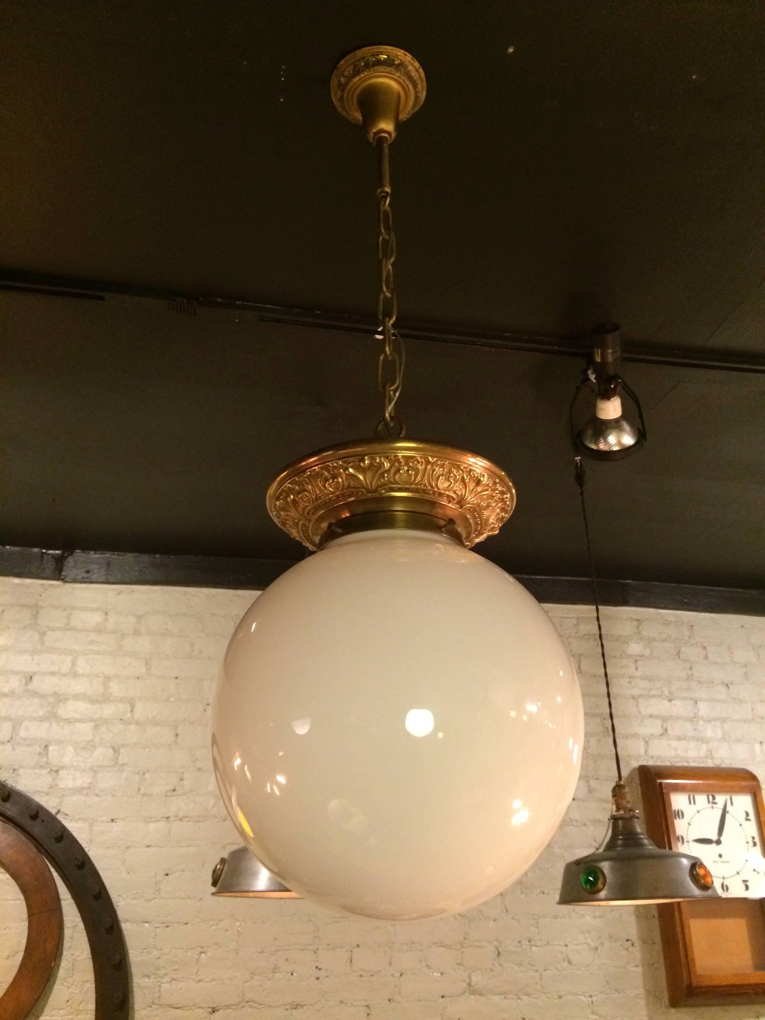 Exceptional and rare, large, handblown, milk glass globe, library pendant light with matching filigree brass fitter, canopy and chain. Brass filigree fitter is a decorative crown to this pendant light and not a flush mount on a chain. Height to top