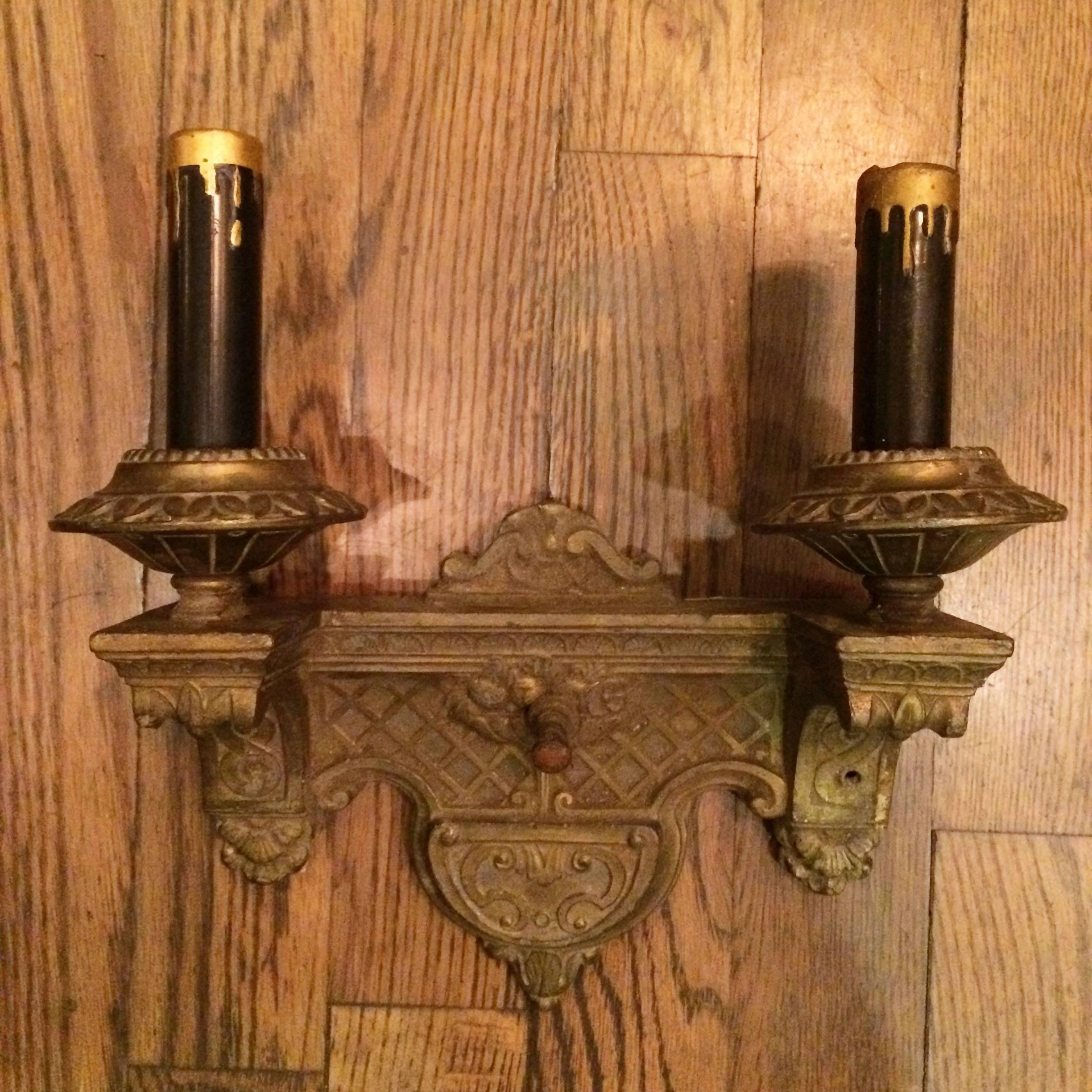 Pair of Art Deco, cast, white metal, wall sconces with switches and two arms on each sconce that accept candelabra bulbs.