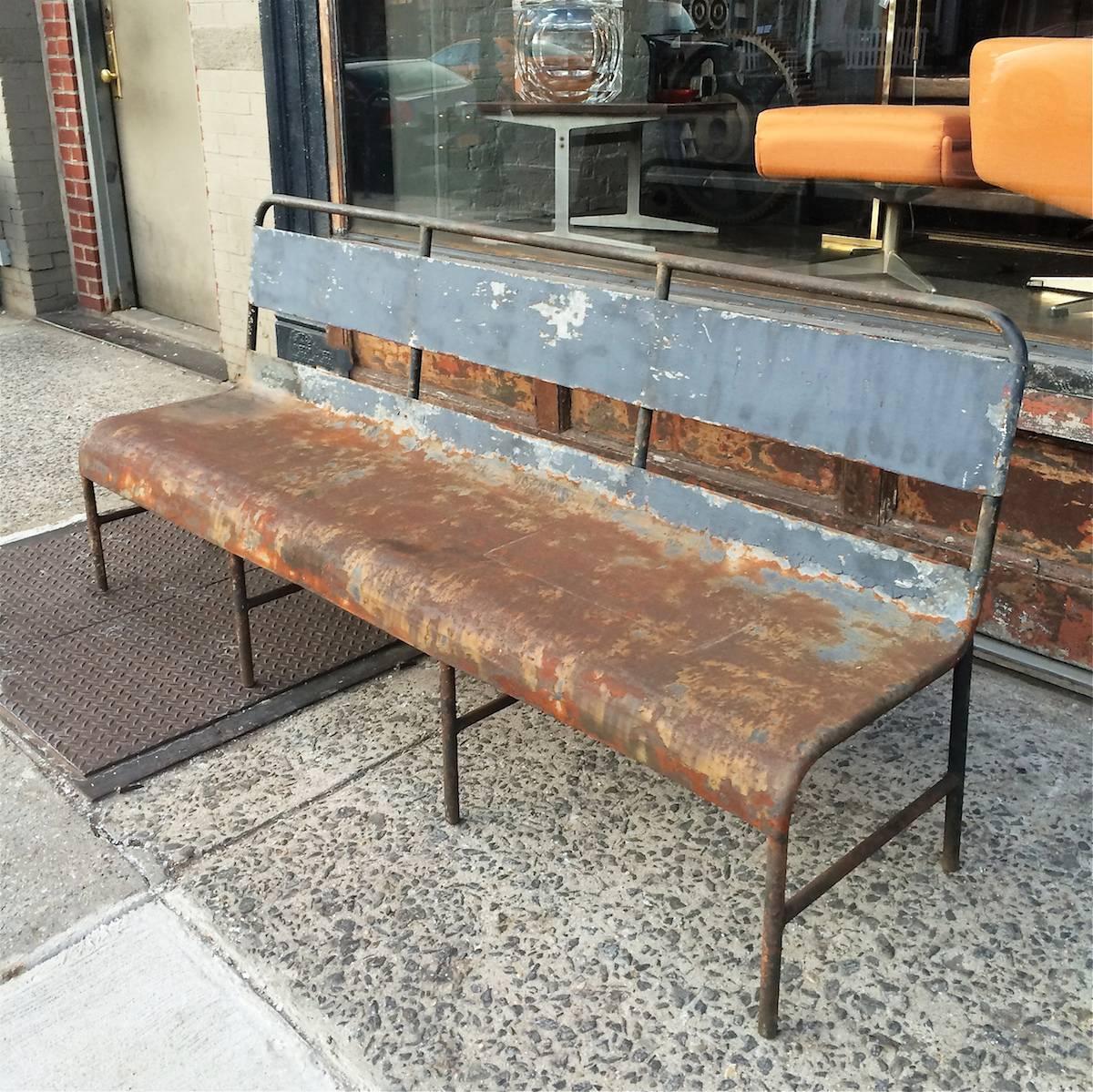 Painted steel, navy ship bench is structurally intact and weathered in a fantastic, rustic industrial patina.