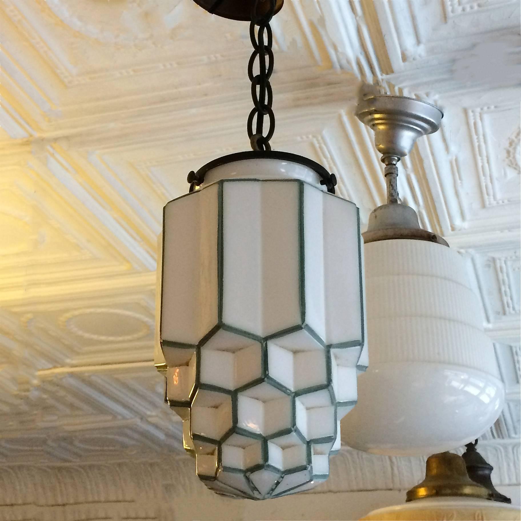 Art Deco pendant light features a tiered milk glass skyscraper shade with green trim on brass fitter, measure: 30