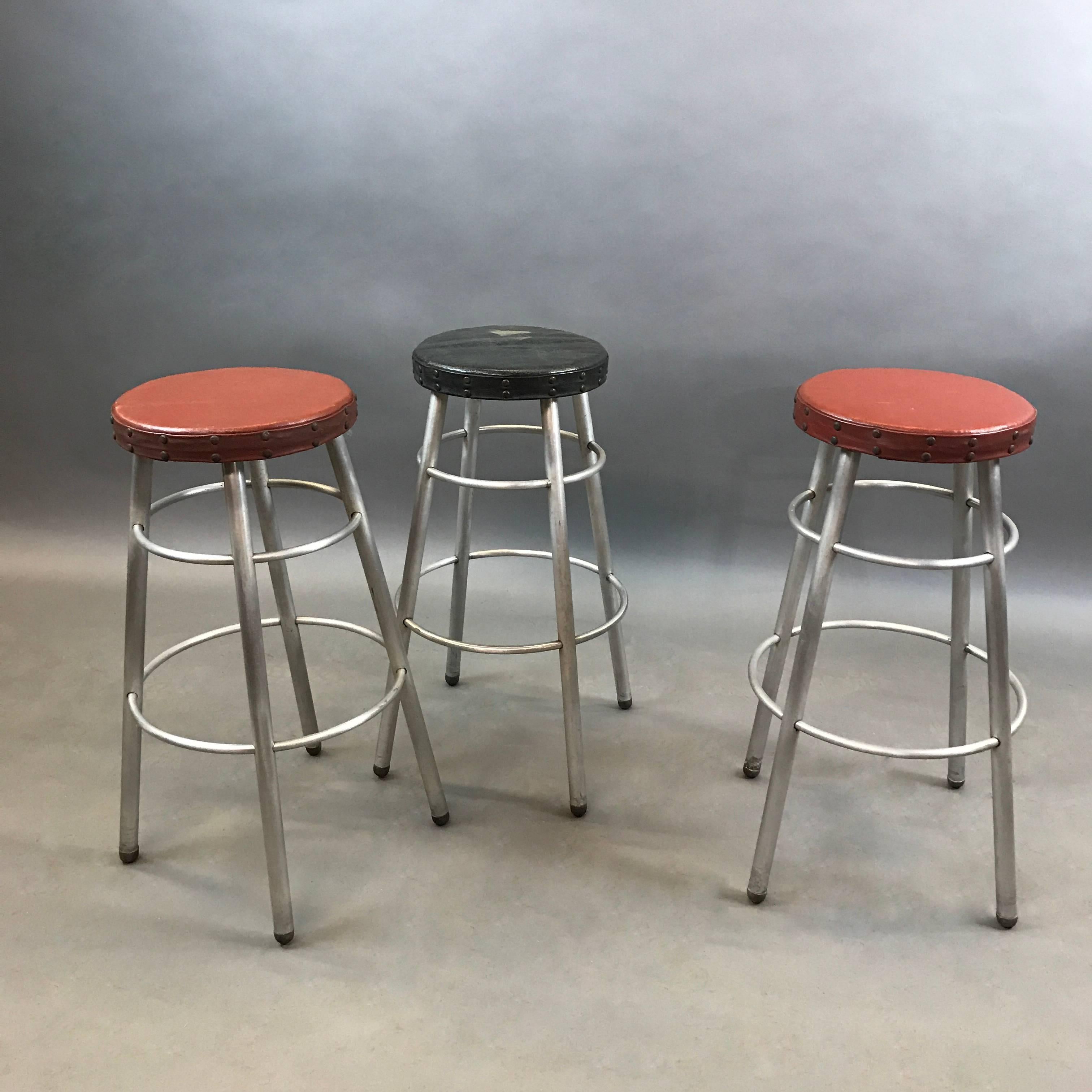 Set of three, machine age, tubular aluminium counter height stools by Alcoa Aluminum Company with original vinyl seats with nailhead trim. Measures: The seat diameter is 12 inches and the footprint diameter is 19 inches.