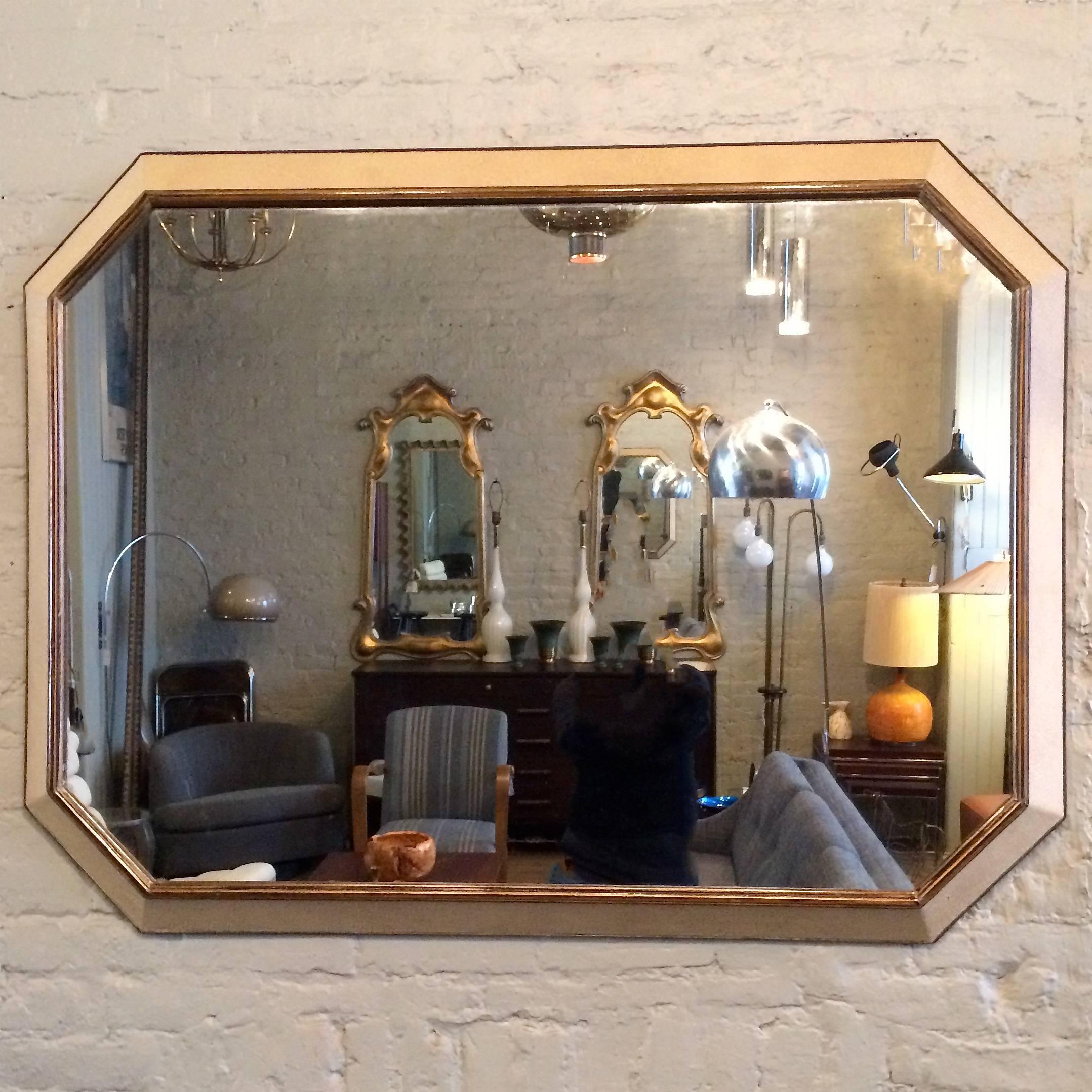 Large, 1940's, mid century, Hollywood Regency, mirror in an elongated, octagonal shape features a customized frame of applied muted gold leather, faux shagreen with a mahogany trim.