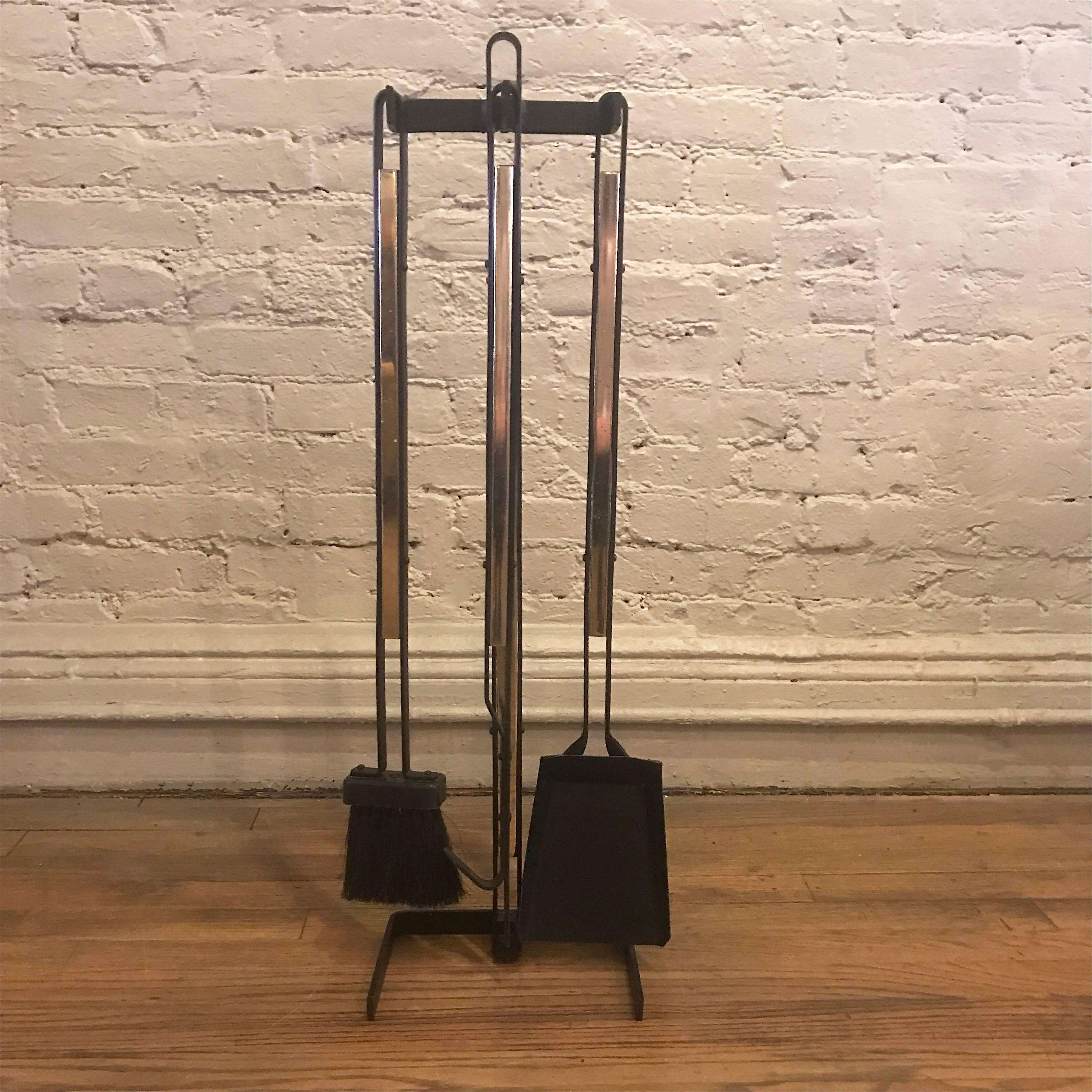 Four piece set of Mid-Century Modern, fireplace tools features looped wrought iron frame and tools with brass inserts. The tools are in great condition showing very little use.