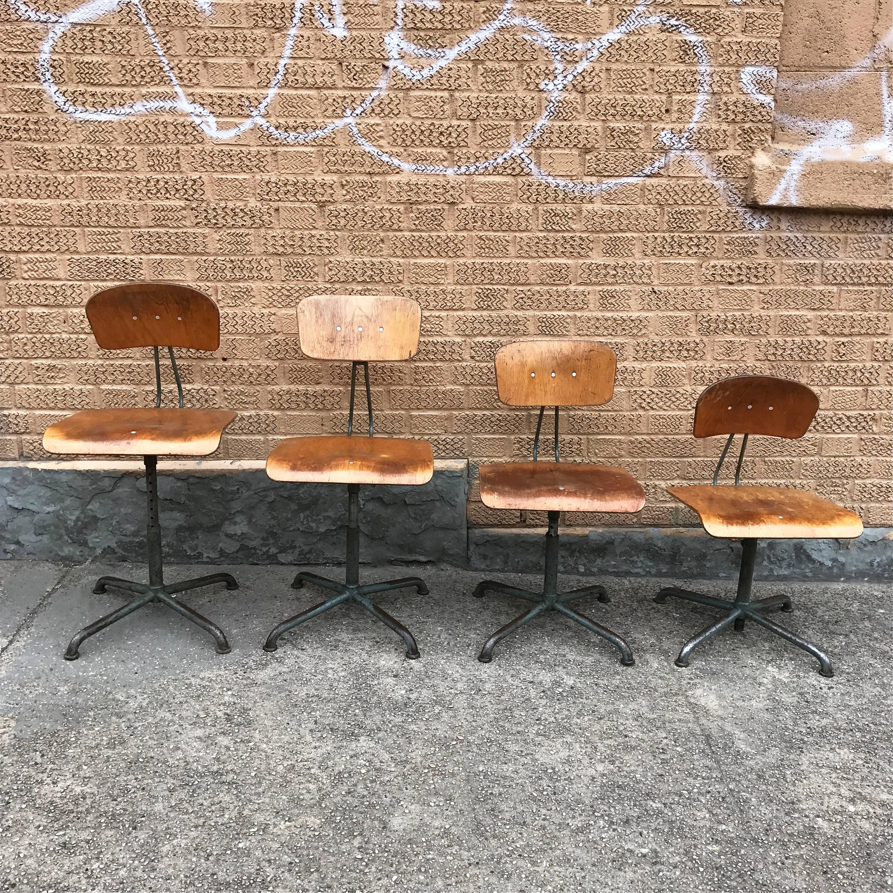 Set of four, Industrial, height adjustable, bent plywood and steel, swivel, shop stools by Swiss maker Basler Eisenmöbelfabrik Sissach, BES feature a well worn patina.

Measures: Seat height adjusts from 15 in-21 in height
Total height adjusts