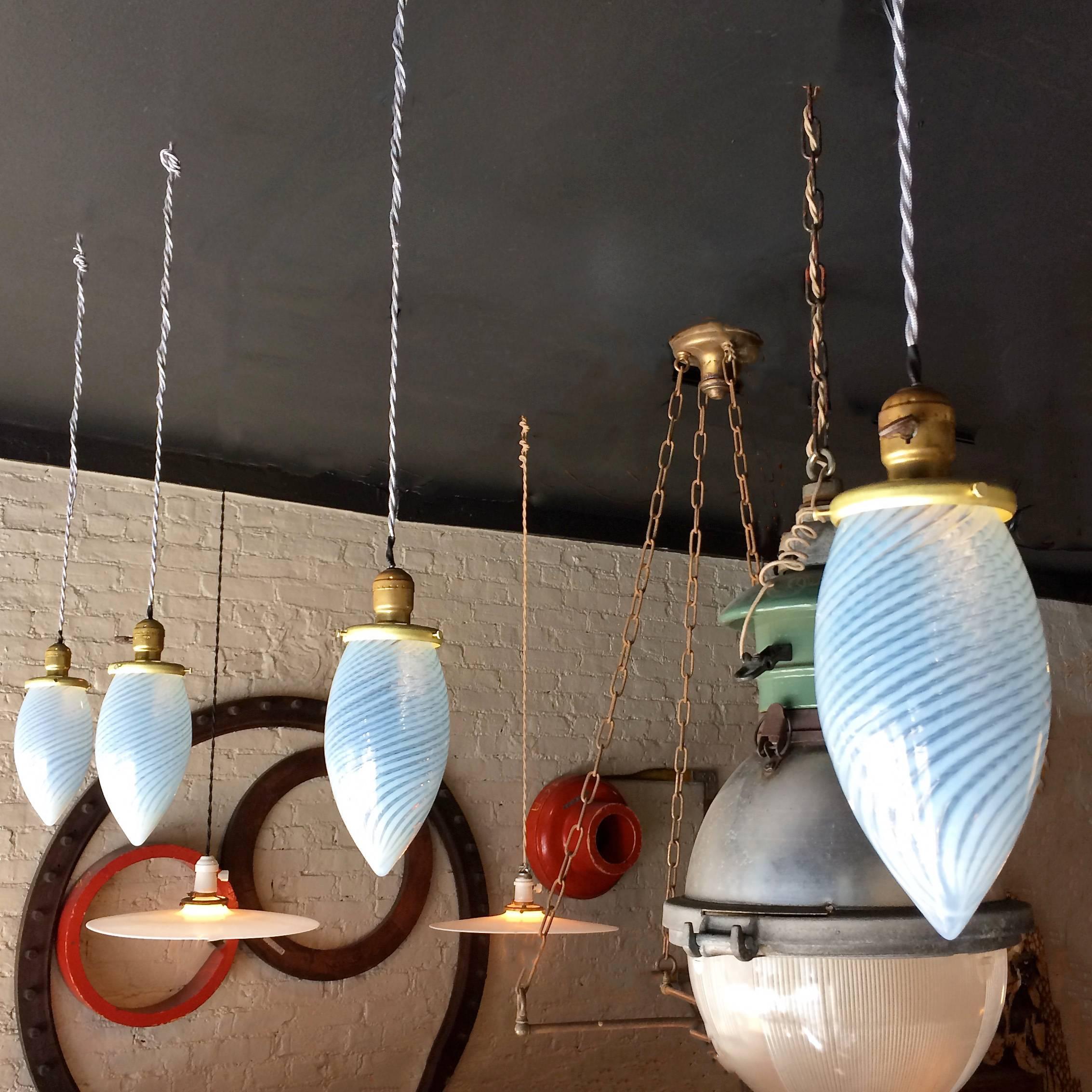 Set of four, pendant lights feature blue swirl, teardrop shape, blown glass shades with brass paddle switch fitters are newly wired with 40in. of grey braided cord and can accept bulbs up to 100 watts. 
