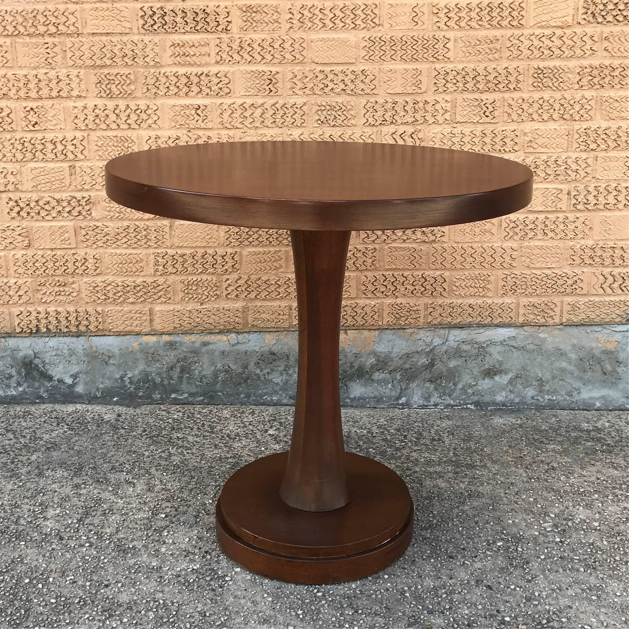 Mid-Century, 1950s, mahogany, pedestal, center table features a solid core with veneer top.