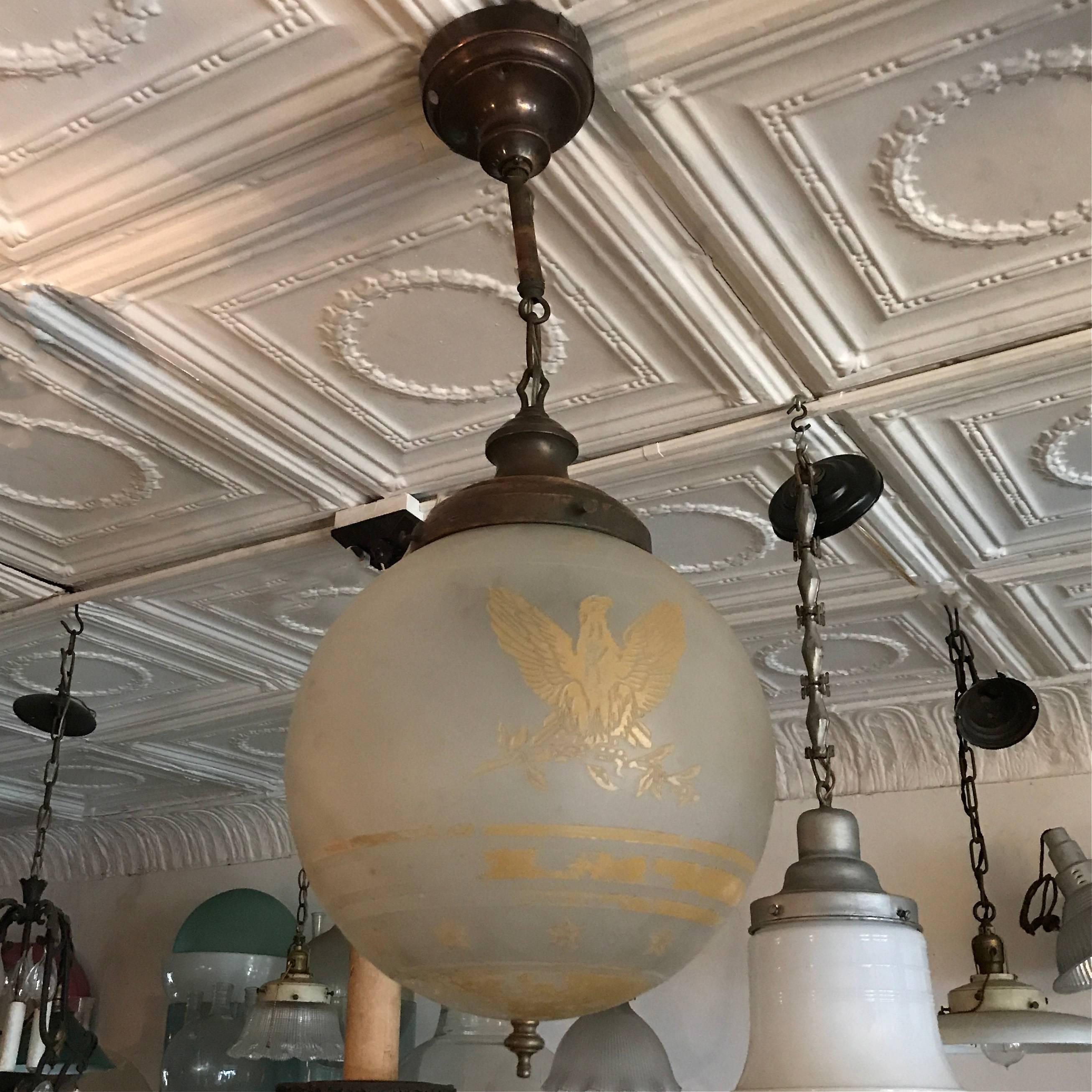 1920s, Federal style, acid etched, frosted glass, globe pendant light depicting American eagle and stars and stripes with brass fitter, chain and canopy. The pendant is newly wired and can accept up to a 200 watt bulb. The fixture is 30