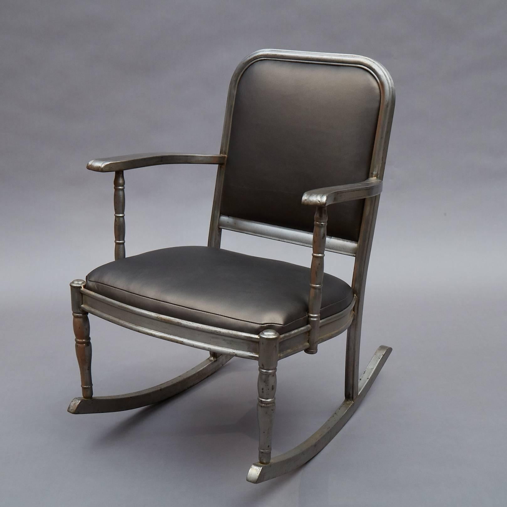Industrial, institutional, brushed steel rocking chair upholstered in a gunmetal vinyl is from the Sheraton Series by Simmons Company Furniture.