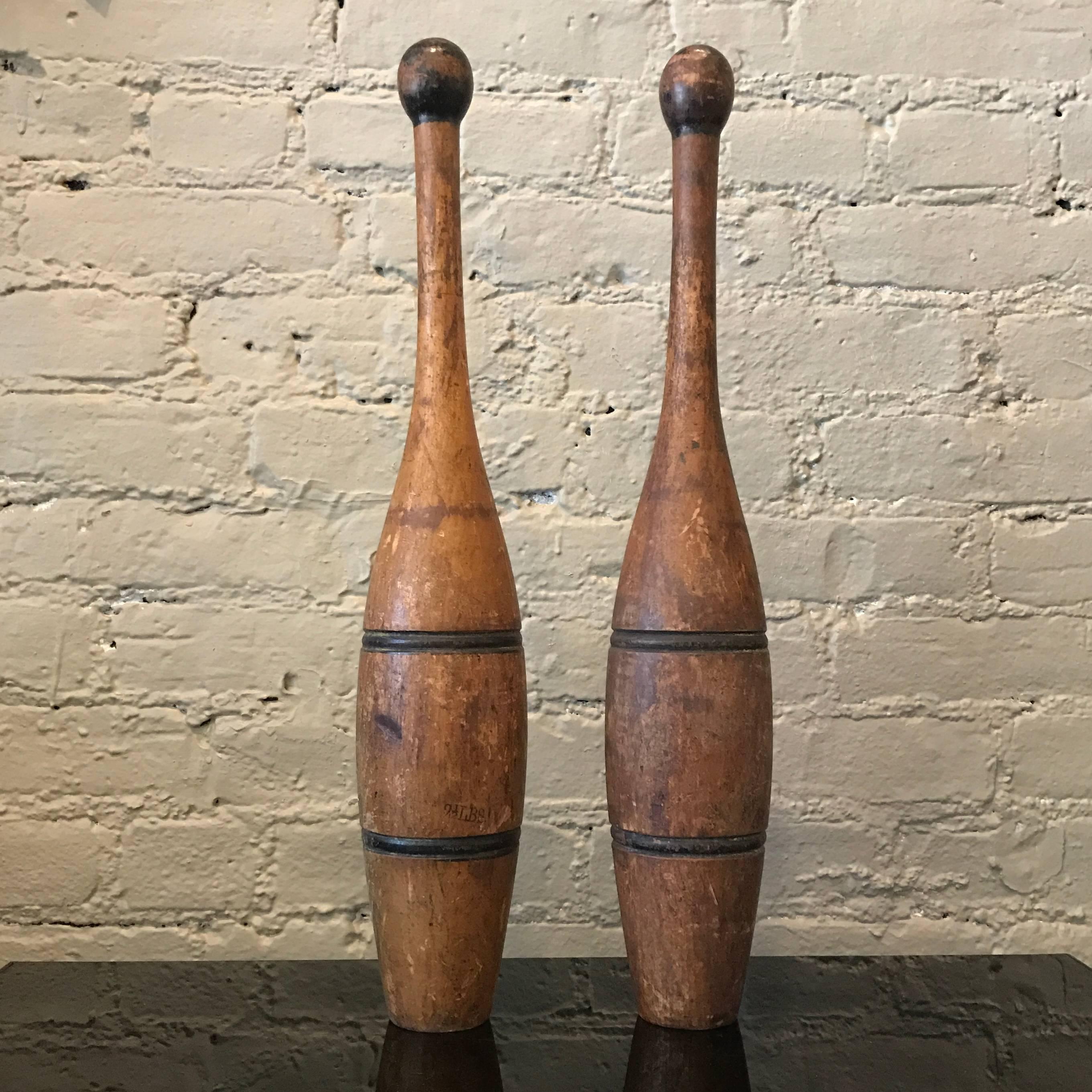 Pair of early 20th century, turned maple wood, striped, juggling pins or “Indian club” feature beautiful, well worn patina.