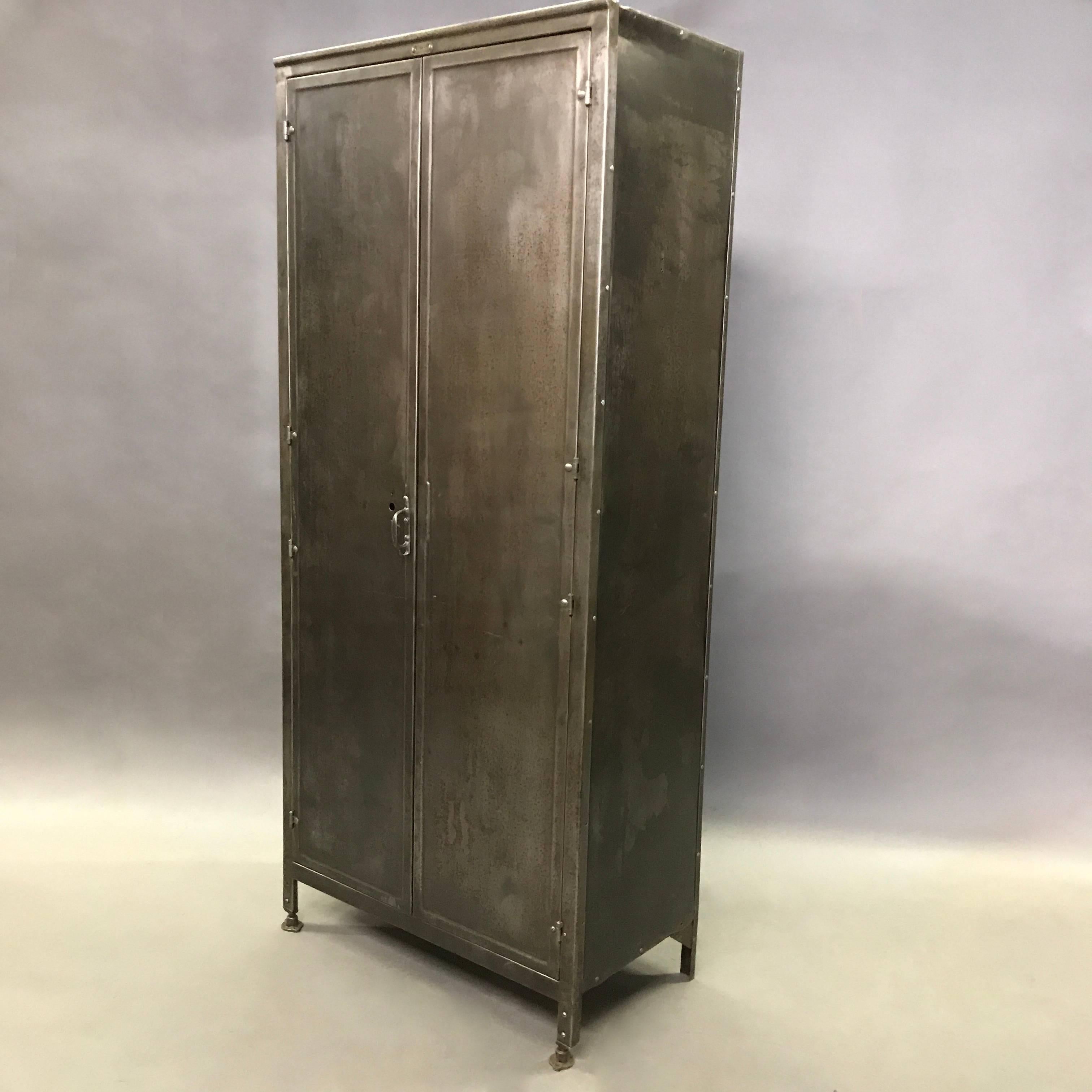 Industrial, double door, brushed steel cabinet by Medart Steelbilt St Louis can be used as a wardrobe or armoire. The interior is contrasted with it's original deep green paint.
