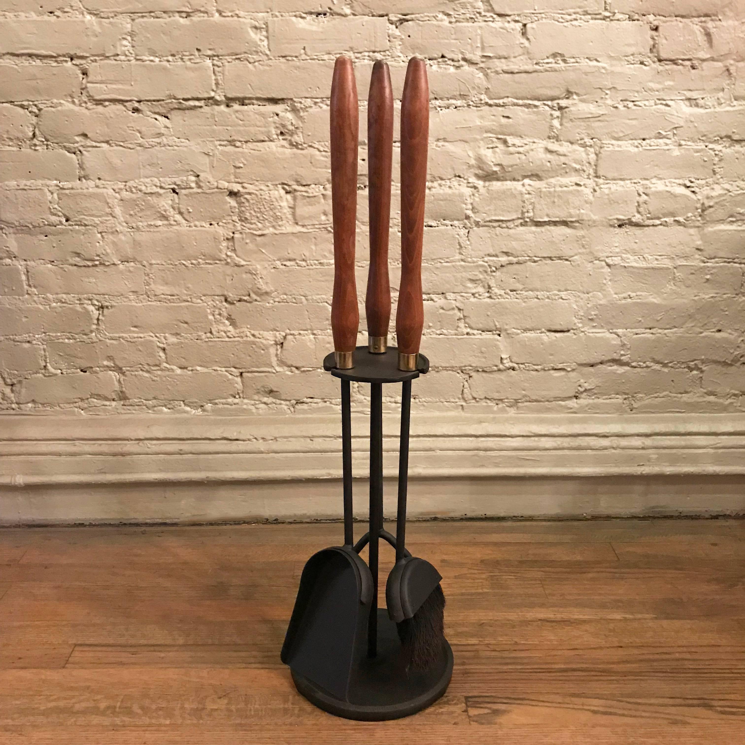 Mid-Century Modern, three-piece, fireplace toolset features a wrought iron stand and tools; stoker, broom and shovel with maple and brass handles.