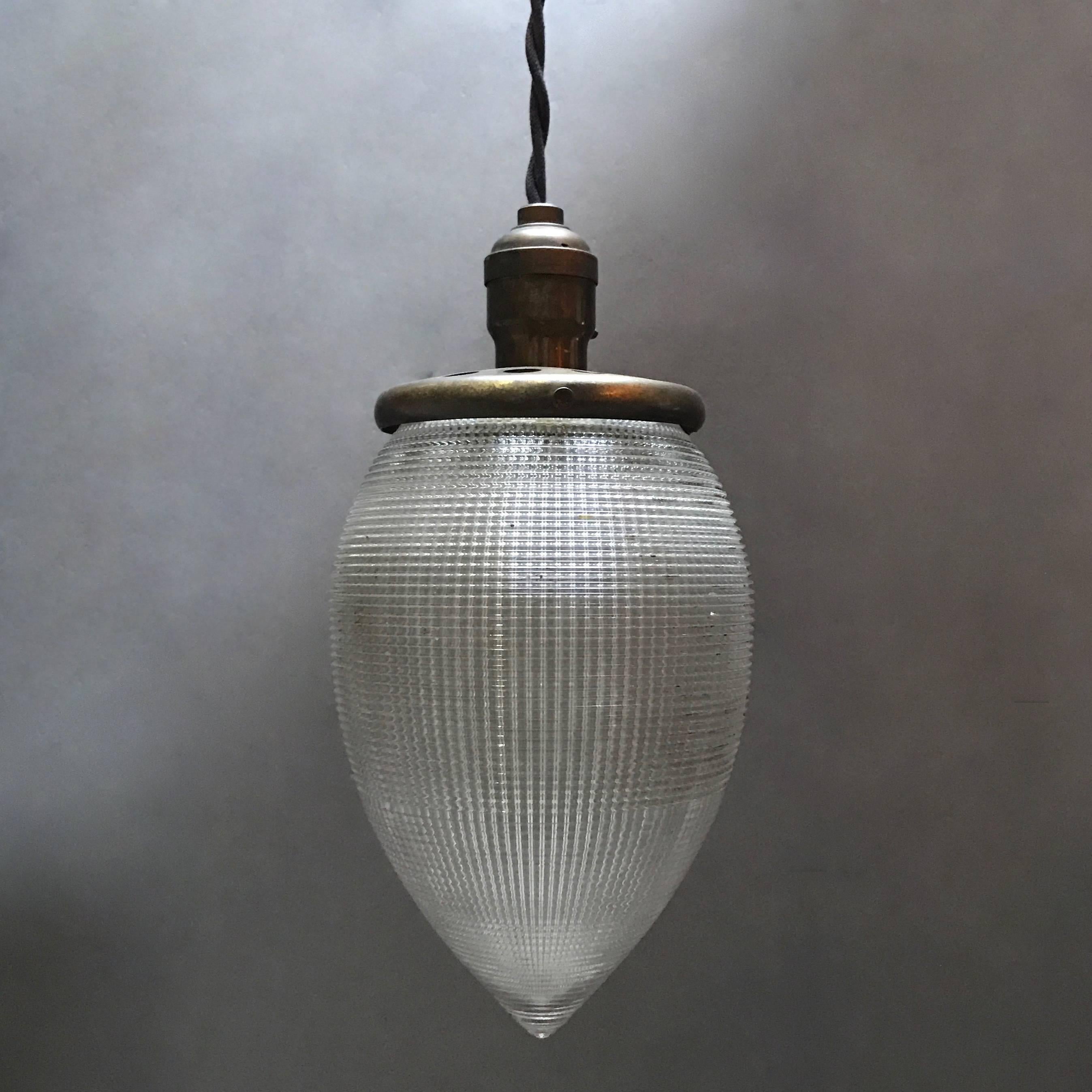 Industrial, Holophane glass, large teardrop shaped, pendant light features a perforated brass fitter and is newly wired with 48in. of black braided cloth cord to accept up to 200 watt bulbs.