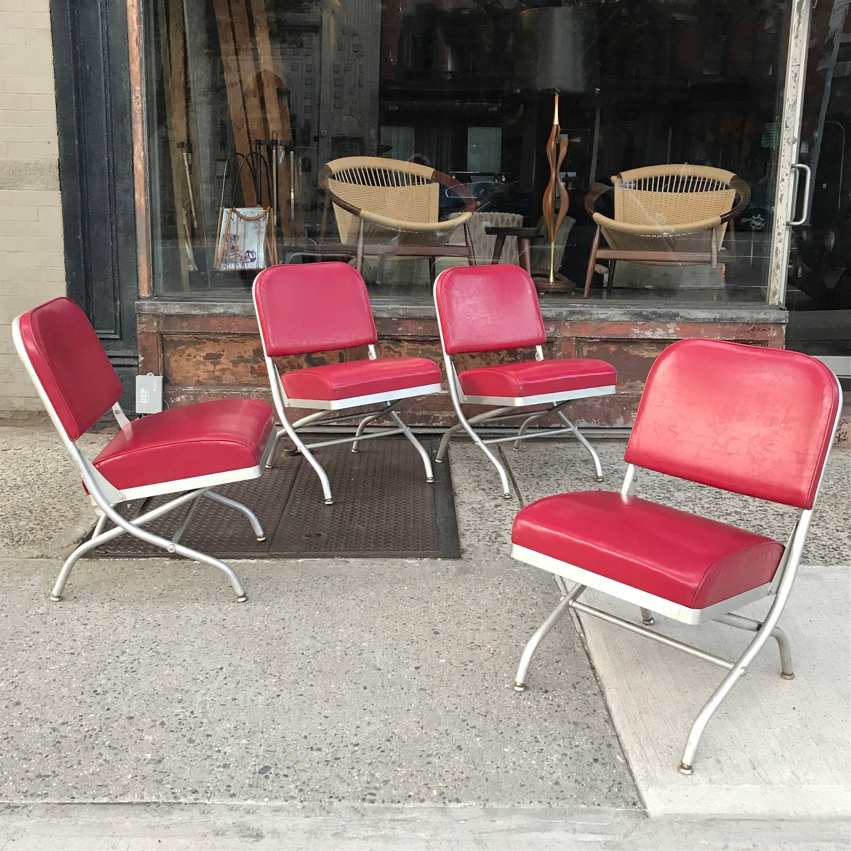 Set of four, mid century, machine age, folding, theater side chairs by Warren McArthur with brushed aluminum frames and lipstick red vinyl upholstery.