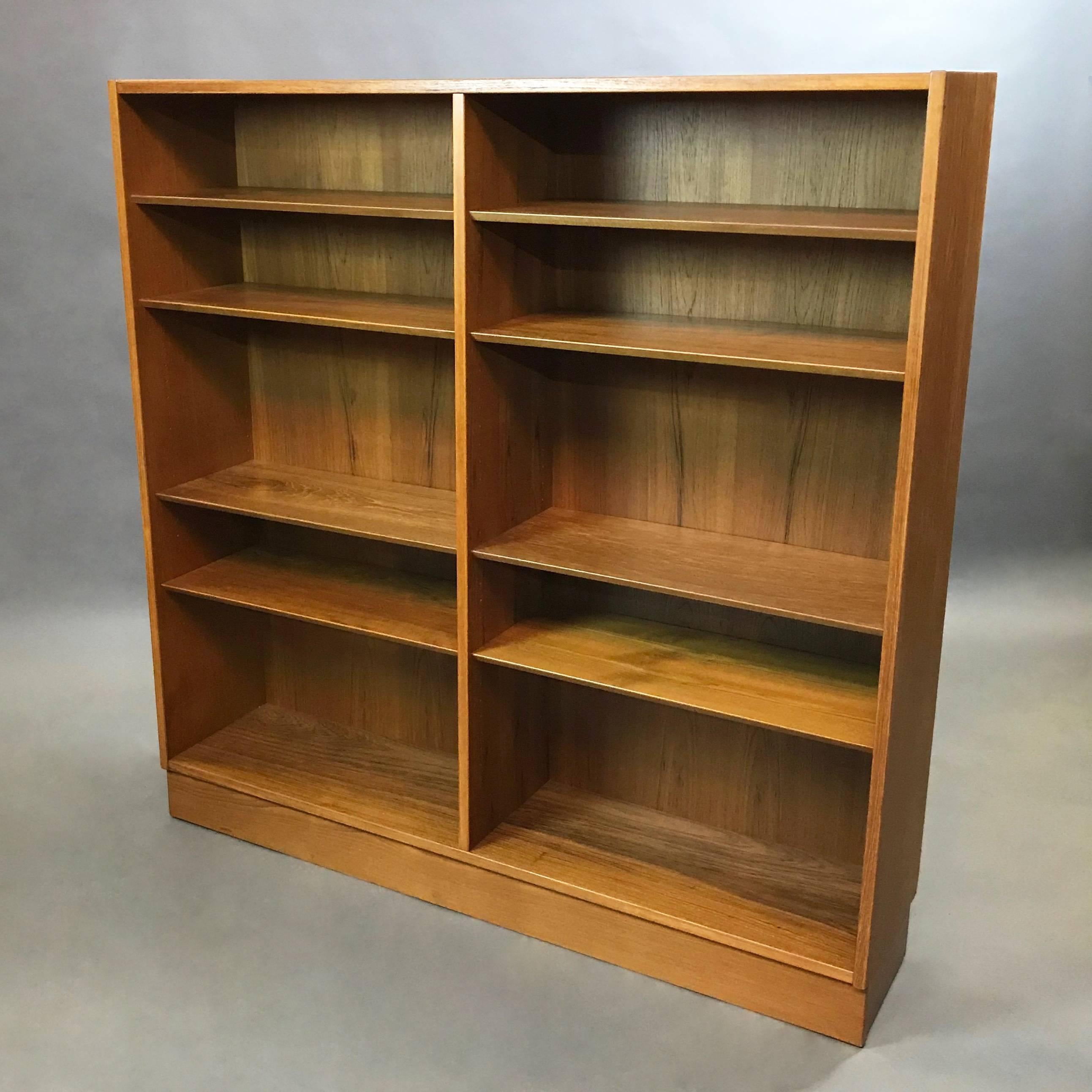Mid-century modern, teak, book case or display cabinet features a middle divider with adjustable shelves with beveled edges. 
