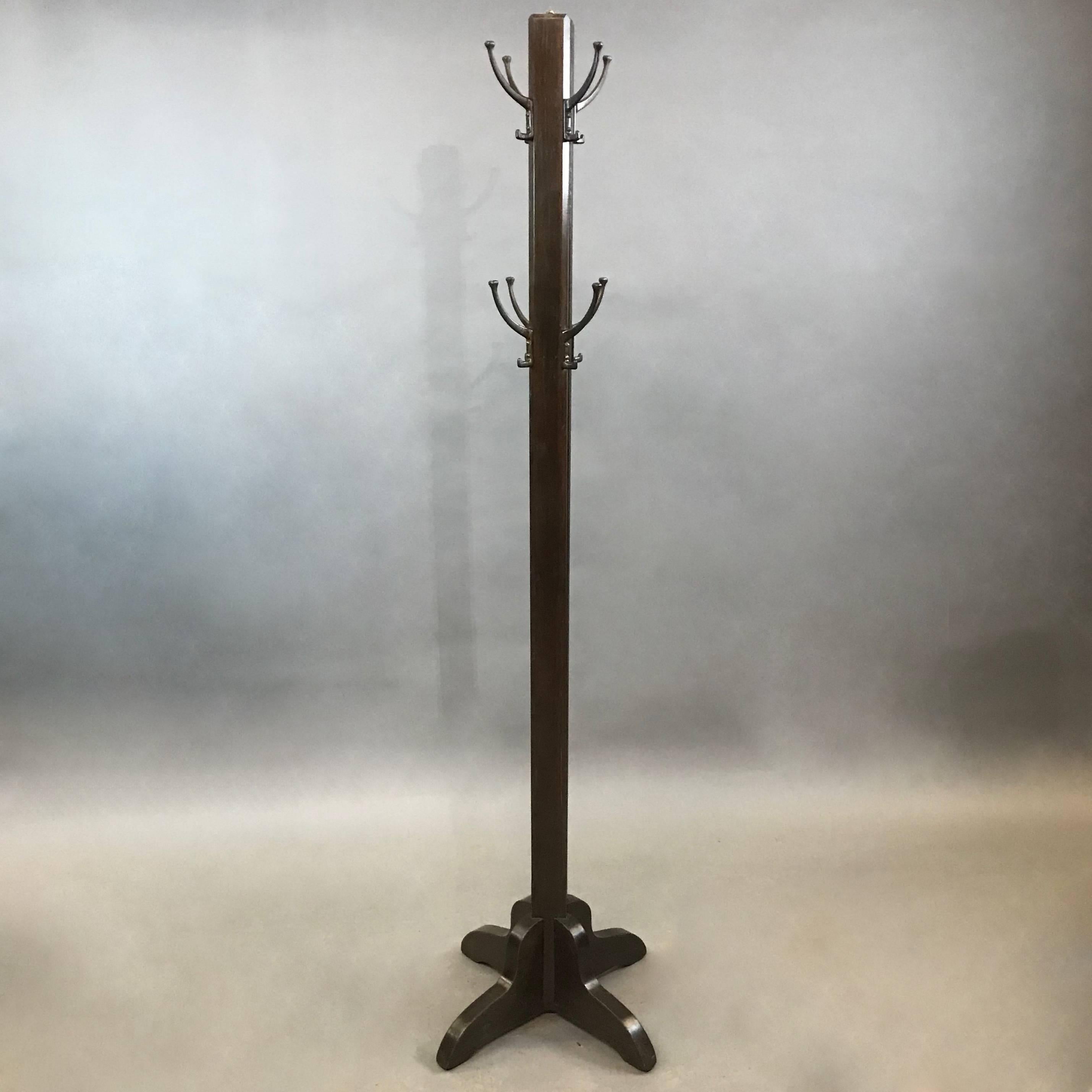 1940s, mid century coat rack with an ebonized poplar stem and 8 large brass hooks, ingeniously opens to expand into a 76in wide, braced rack for additional hanging space.