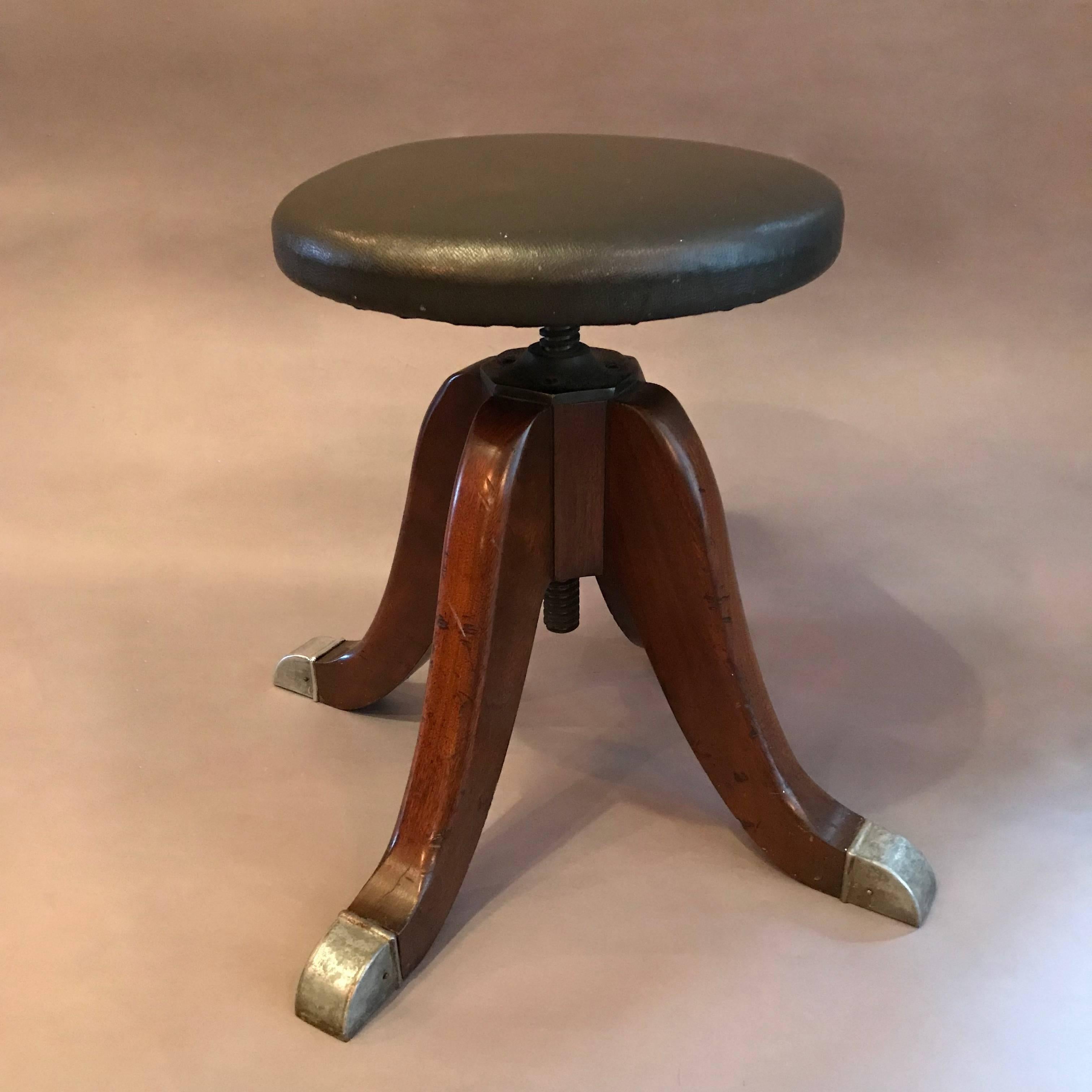 1930s, swivel, medical, optometry examination stool features a black leather seat, wood legs with steel tips. Measure: Seat height is adjustable from 17 - 22 inches.