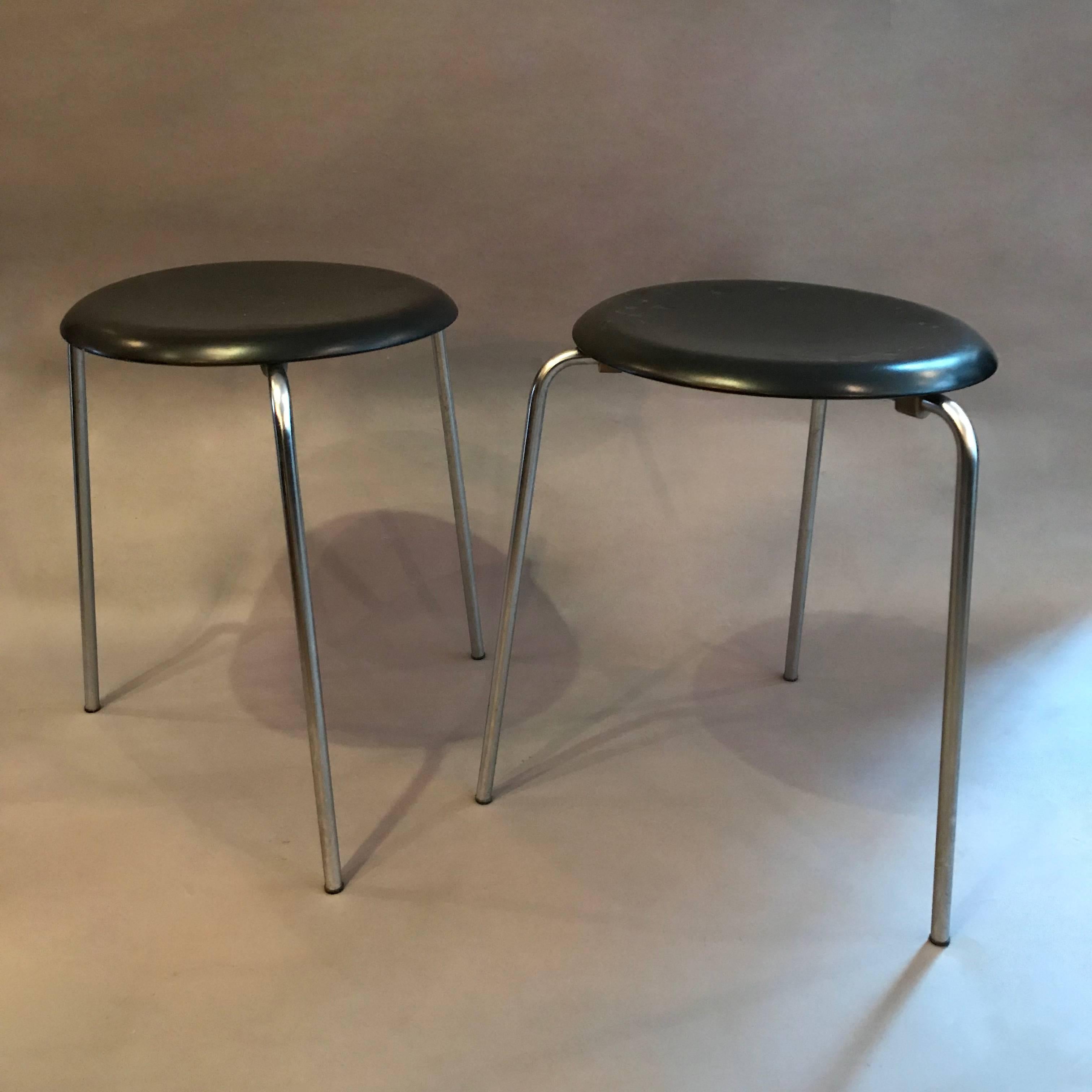 Pair of Danish modern, stacking, Dot stools by Arne Jacobsen for Fritz Hansen features nickel-plated tubular steel legs and a black lacquered, molded wood, 13 in diameter seats.